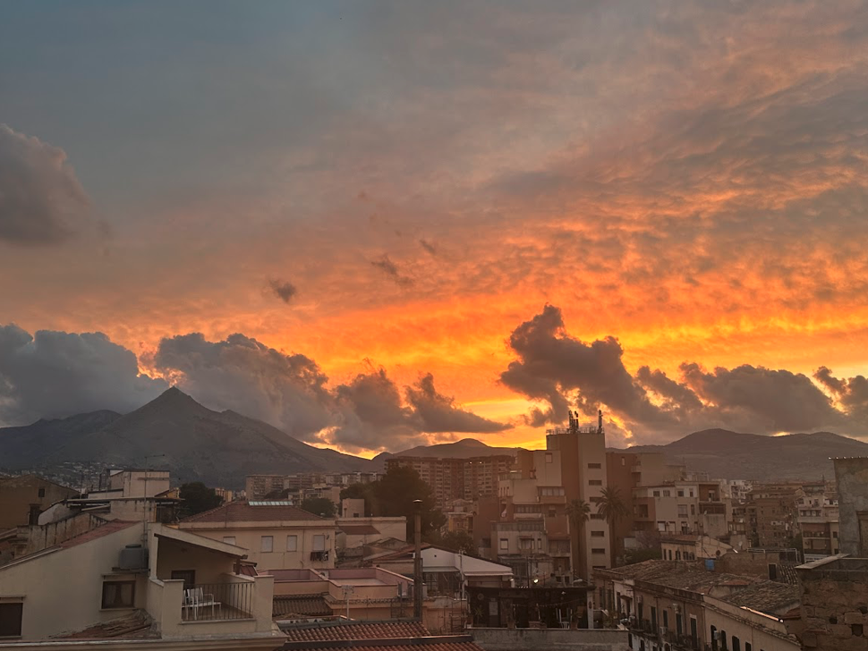 A sunset with vibrant colors over an old city. There is a mountain in the background.