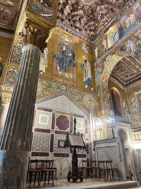 The interior of a chapel with a book on a stand and wall murals.