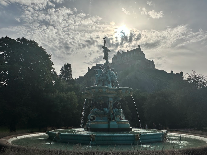 Blue fountain with a large castle on the hill behind it.