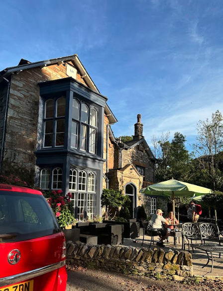 An old stone hotel with blue-framed bay windows and patio tables out front.