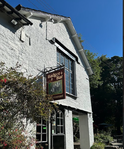 A white stone building with a sign that reads "Badger Bar Restaurant" and has artwork of two badgers.