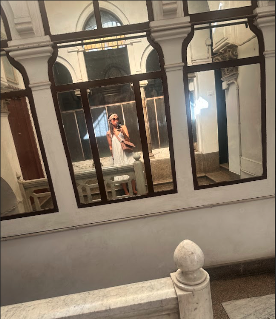 A woman taking a selfie in a large mirror in an old building.