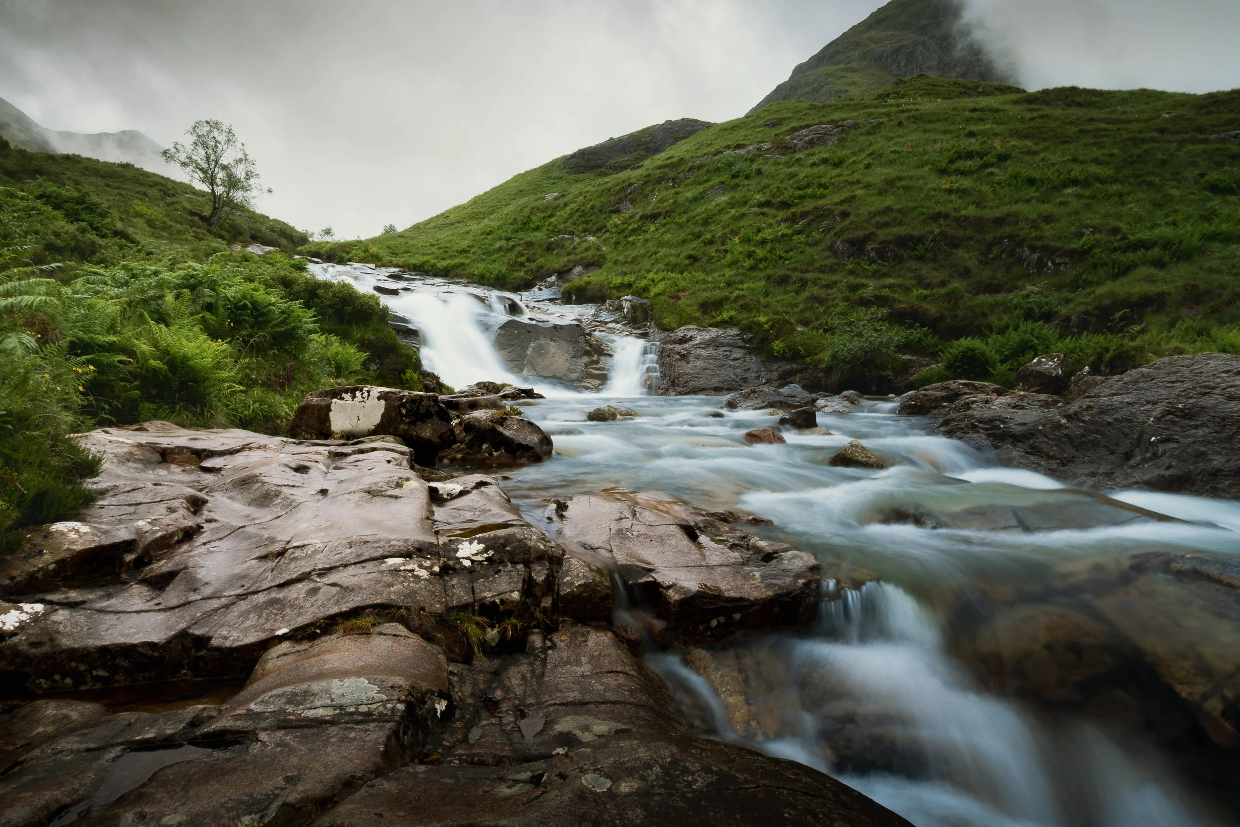 A picture of a river flowing through moody mountains