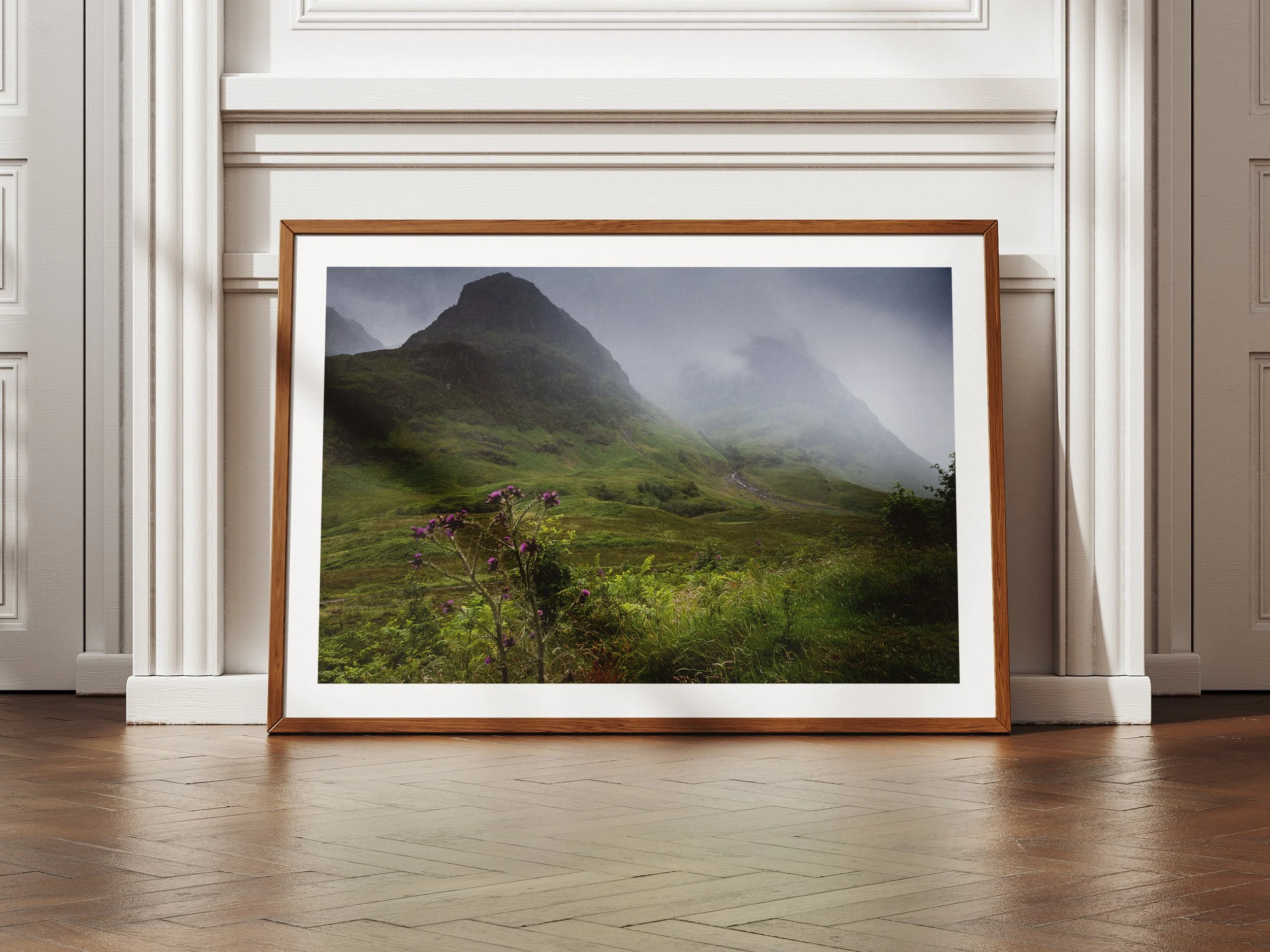 A framed picture of the three sisters of Glencoe under moody skies