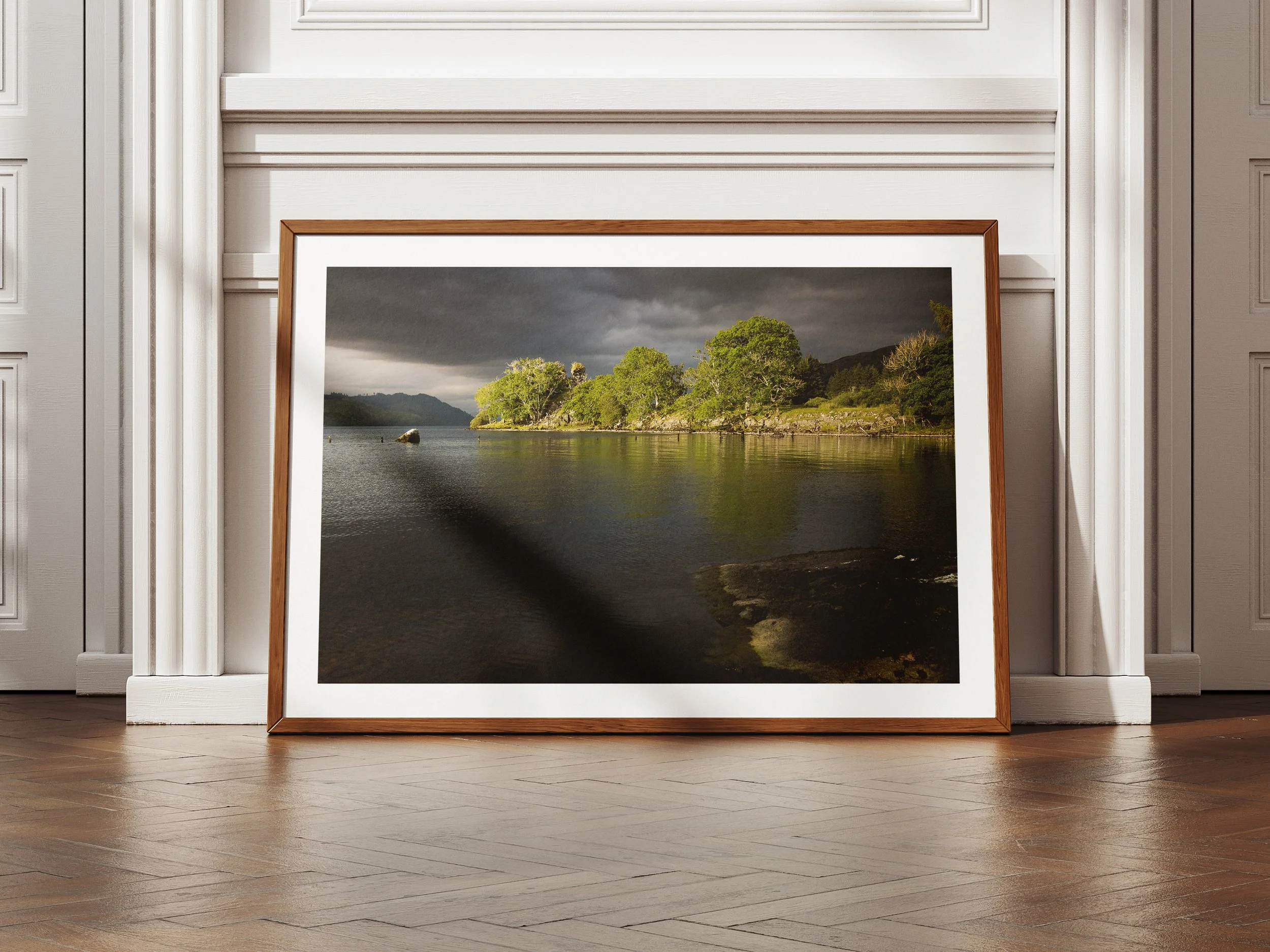 A framed picture of castle ruins across a loch covered in dense foliage