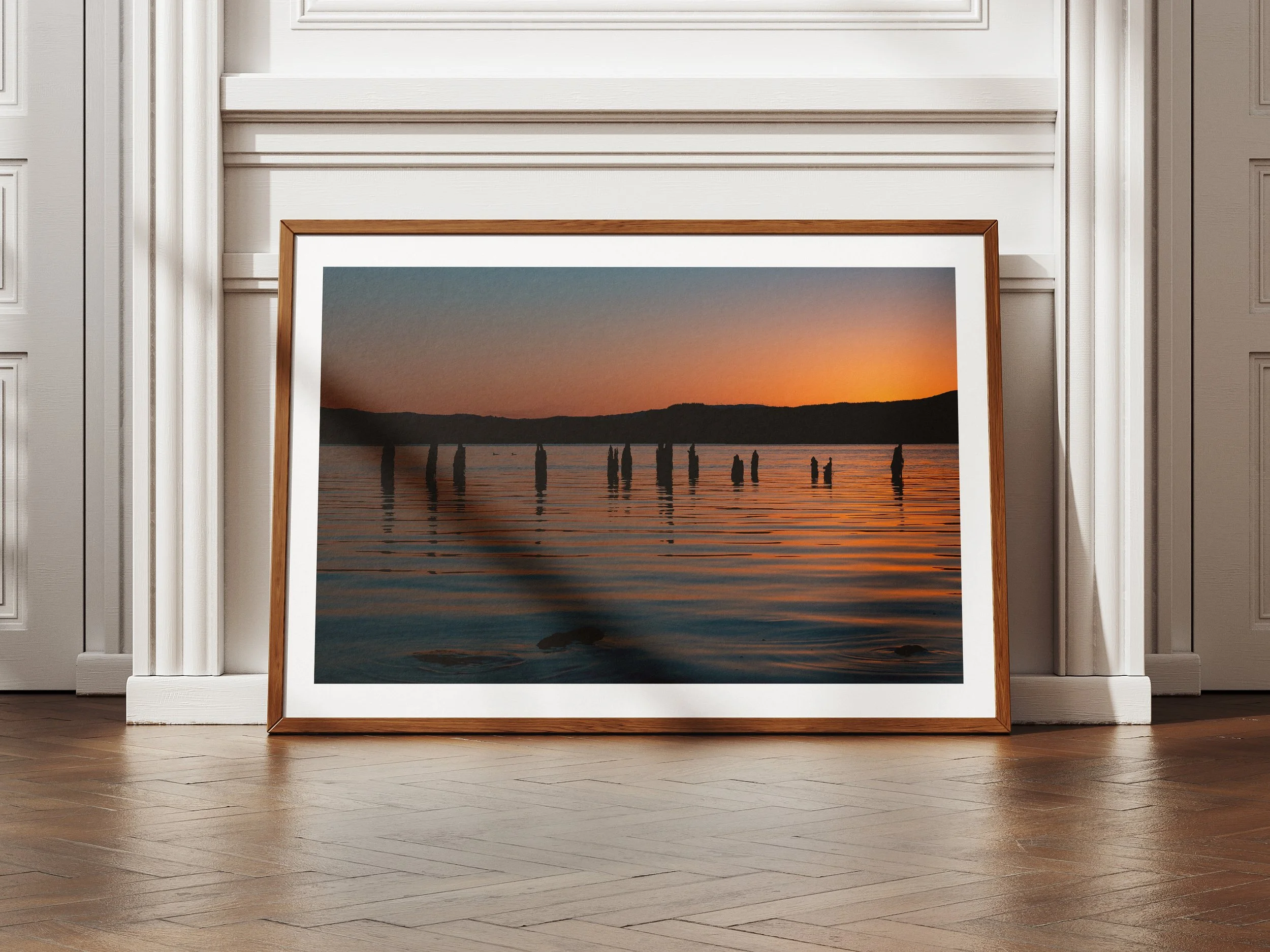 A framed picture of a sunset over loch awe with the remains of an old pier in the distance