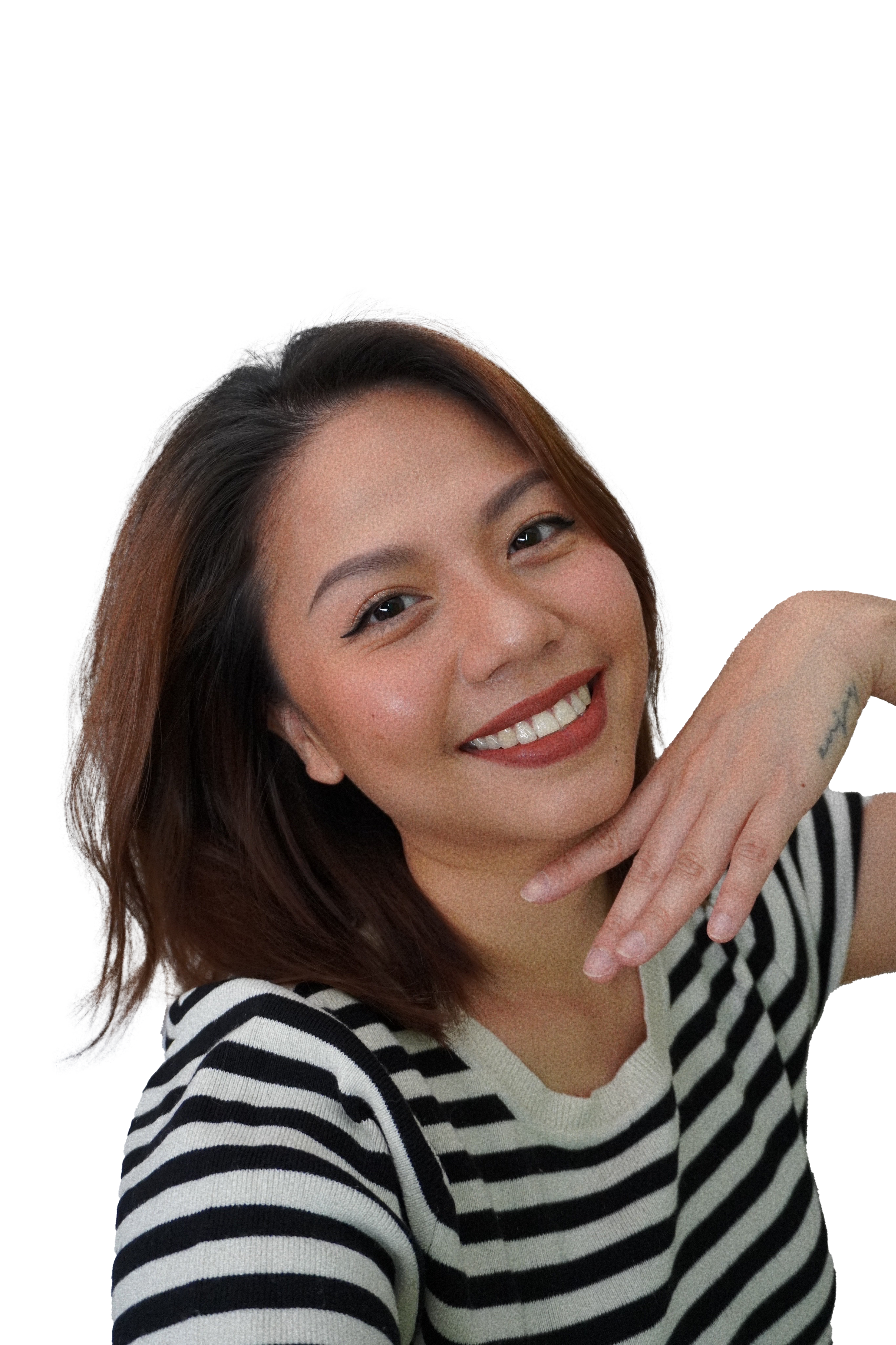 A smiling woman with medium length reddish-brown hair, wearing a black and white striped shirt, resting her chin on her hand with a tattoo visible on her wrist.