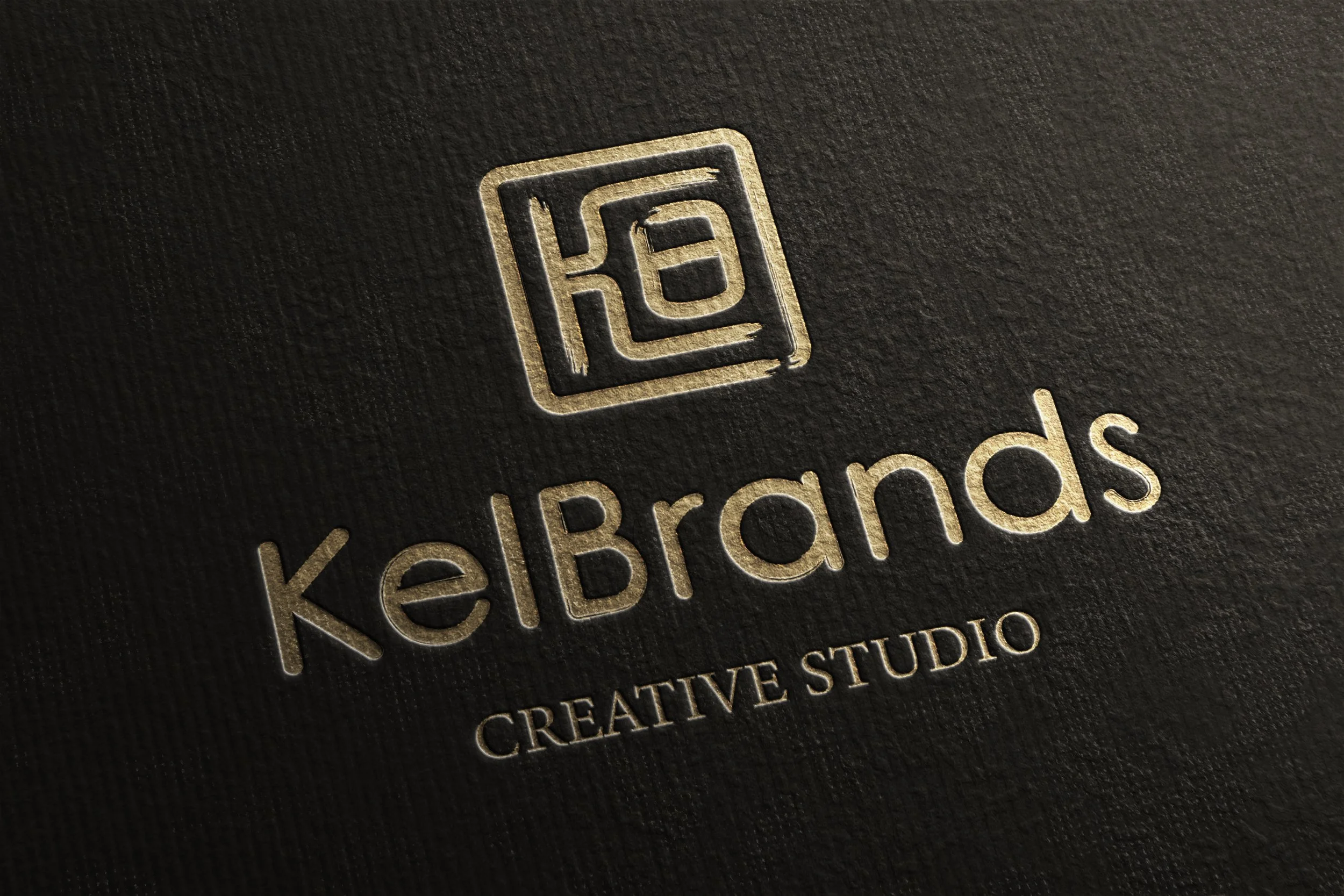 Gold embossed logo and text on a dark textured surface, displaying the brand name KelBrands and the tagline Creative Studio.