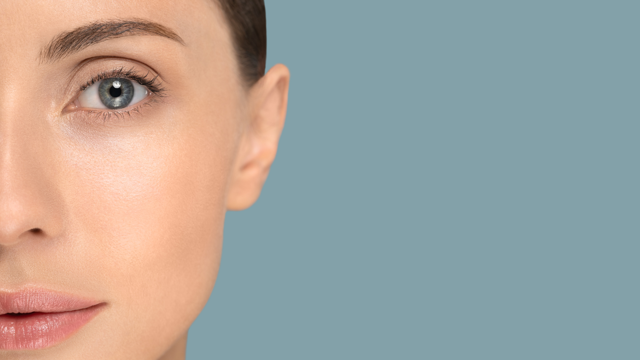 Close-up of a woman's face, showing her left eye, eyebrow, cheek, and part of her lips against a blue background.
