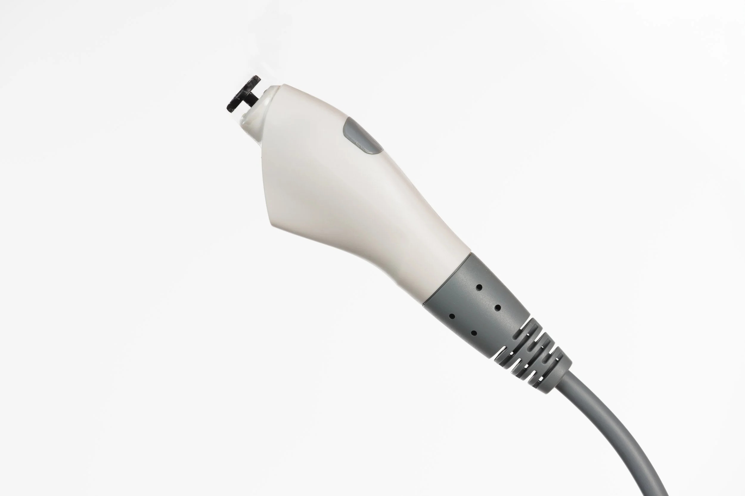 Close-up of a person's hand holding an asthma inhaler with a gray tube extending from it.