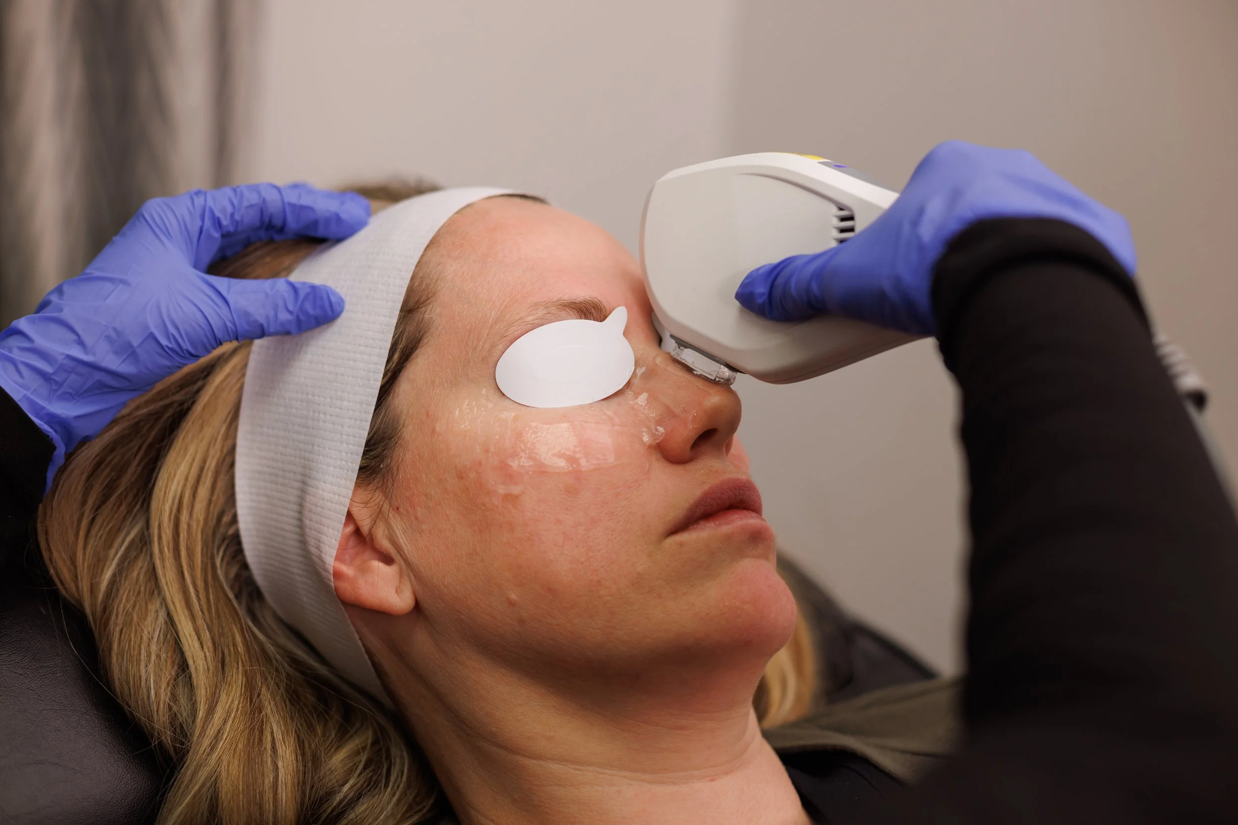 Close-up of a person's hand holding a small, white, handheld device with a flat, rounded shape and multiple ventilation slots, against a plain background.