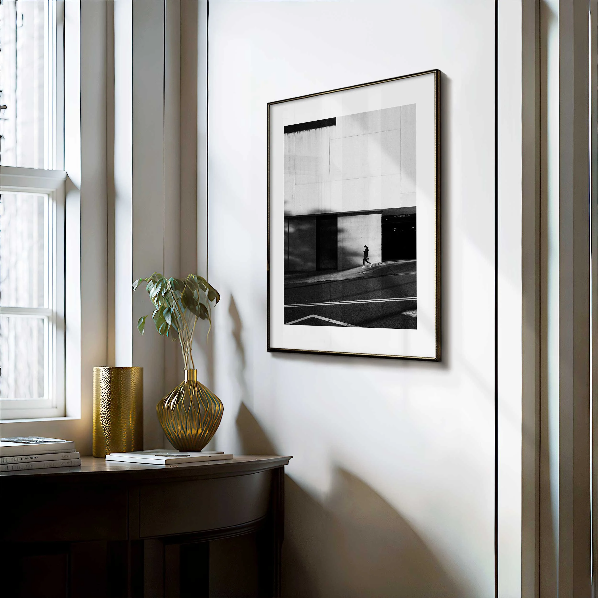 Black and white street photograph of a lone pedestrian walking through a shaft of light beneath a large geometric concrete facade in Sydney.