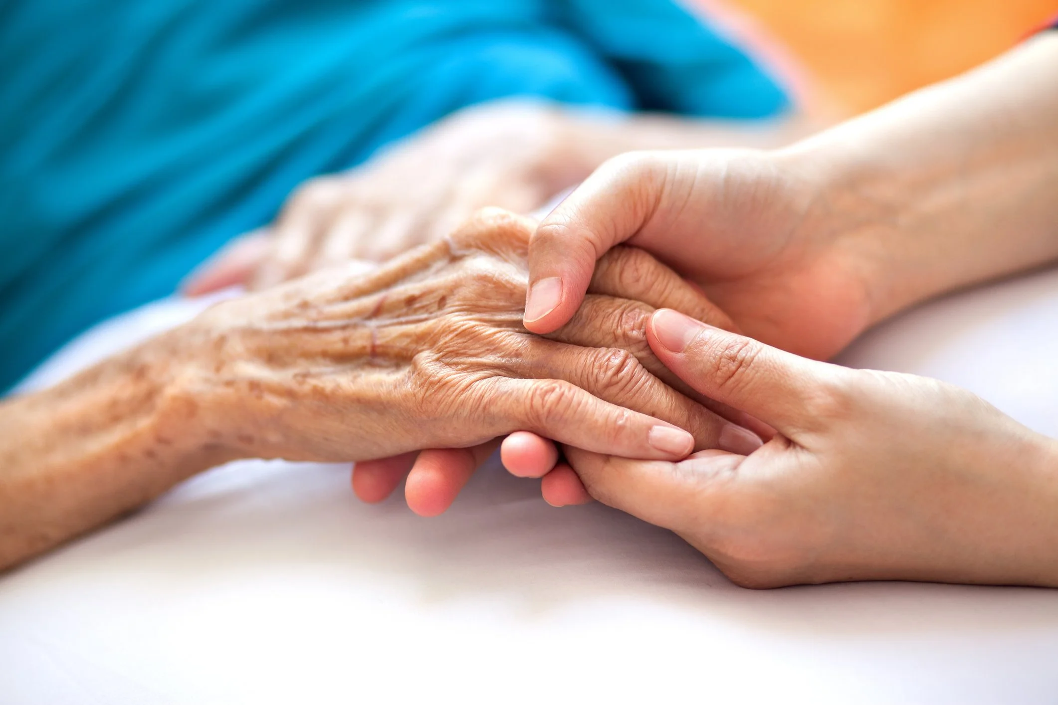 Close-up of a young person's hand holding and supporting an elderly person's hand, conveying care and compassion.