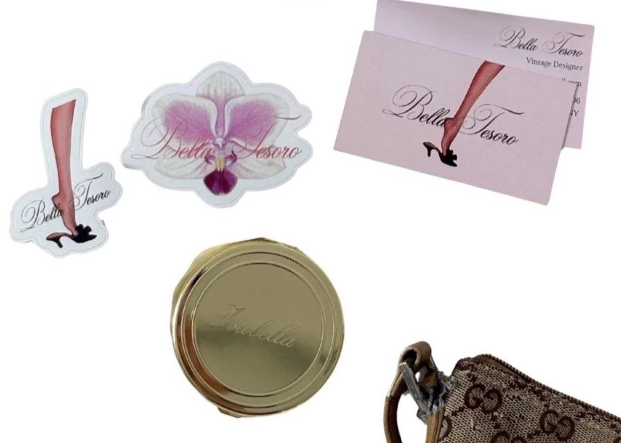 A set of stickers with the words "Bella Tesoro," including one shaped like a leg with high heel shoe, and a purple orchid flower sticker. There are two pink business cards with a leg and high heel shoe illustration, and a round gold tins with "Bella Tesoro" engraved on the lid, along with a Louis Vuitton patterned bag with a beige and brown design.