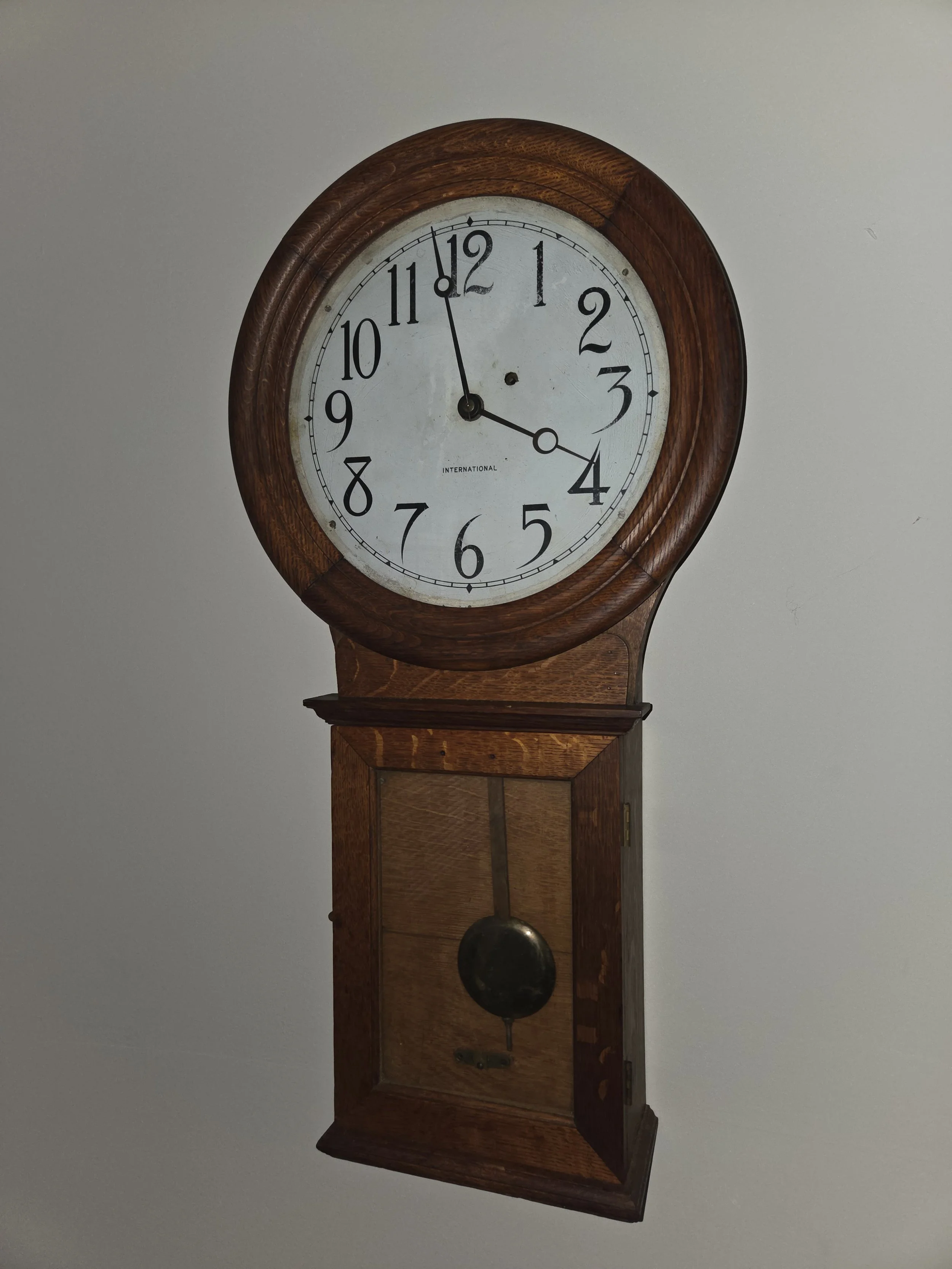 A wooden wall clock with a white face, black numbers, and two black clock hands, showing the time as 11:20.