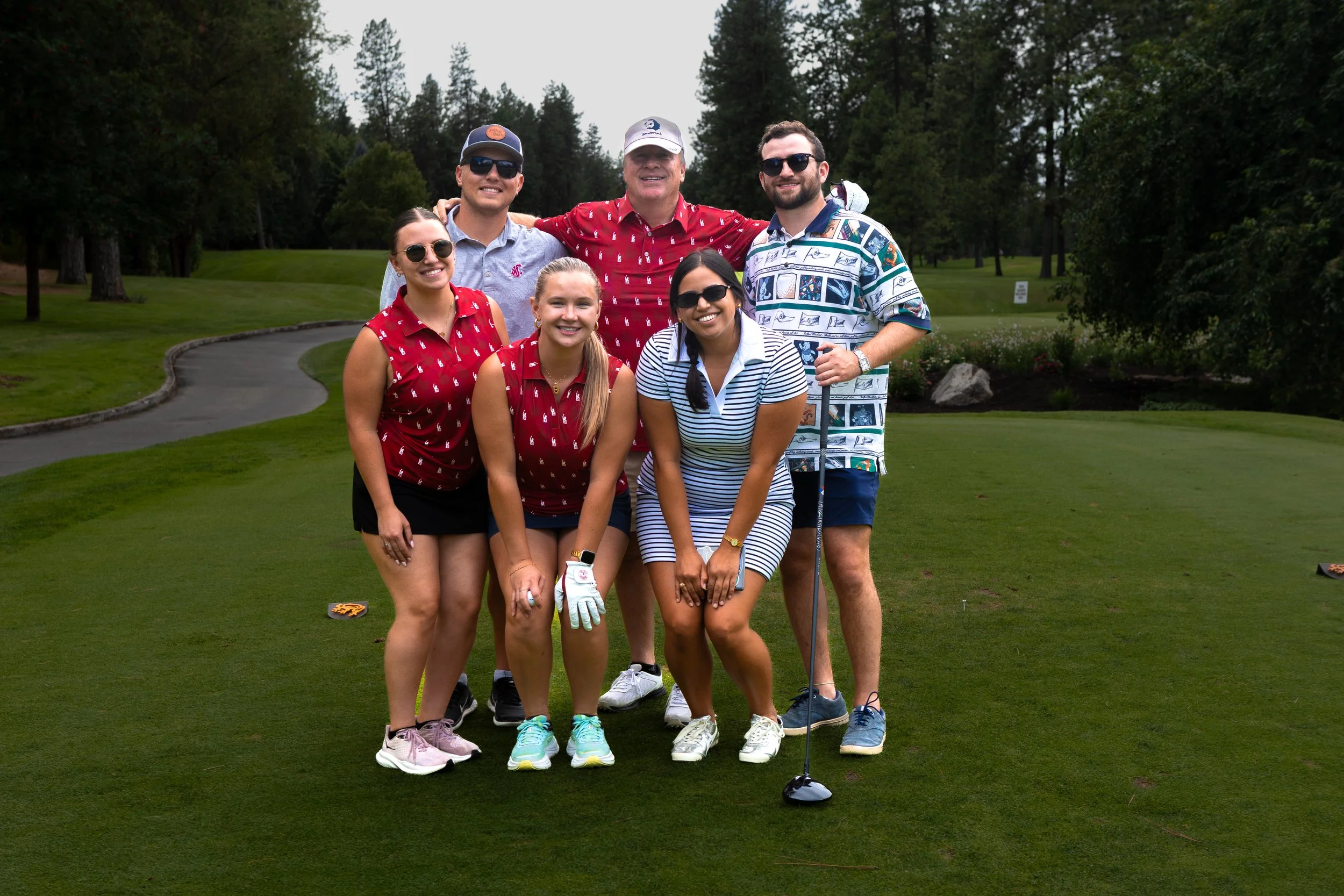 Group of six people in golf attire posing for a photo