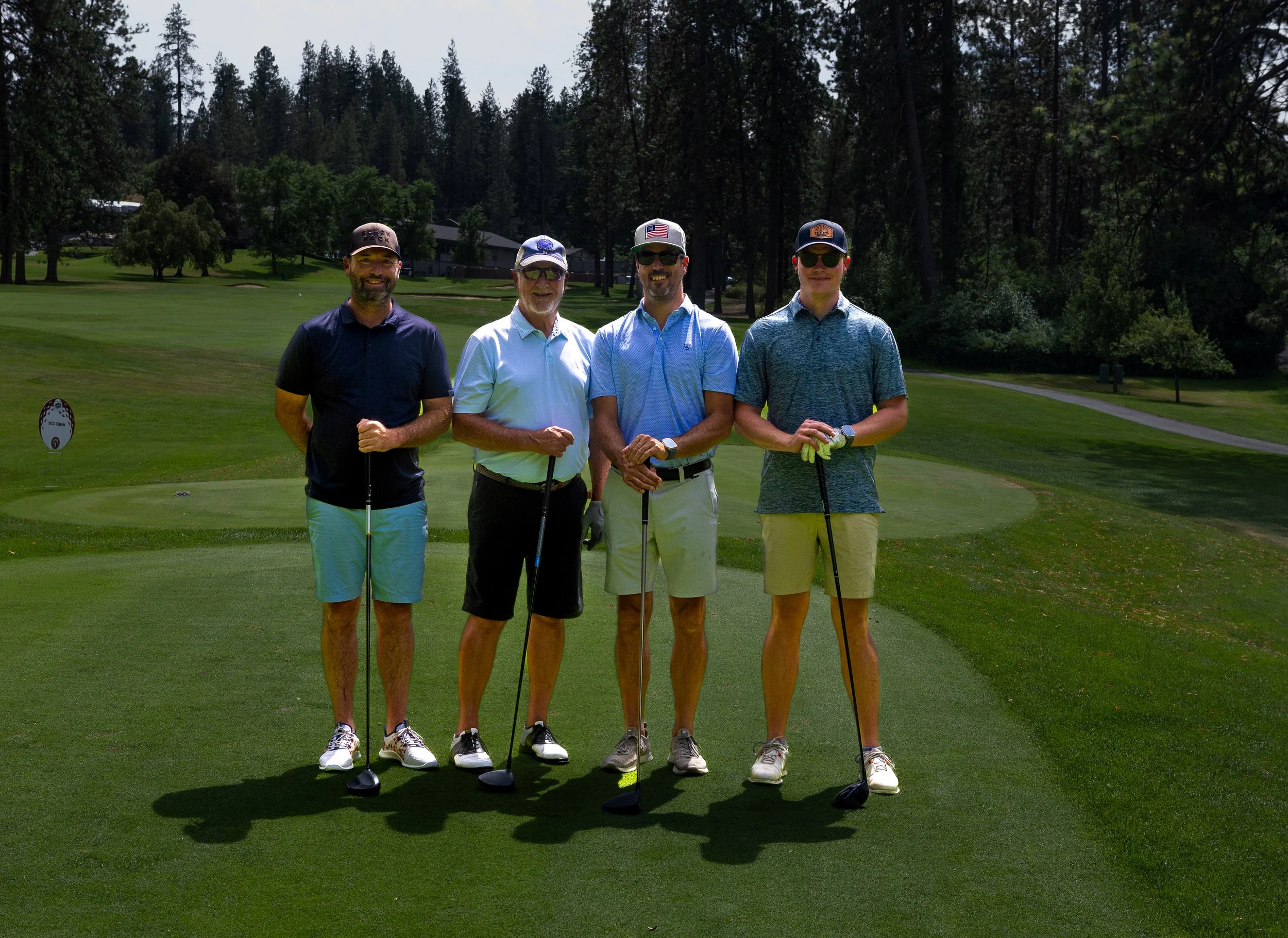 Four men in gold attire standing holding golf clubs