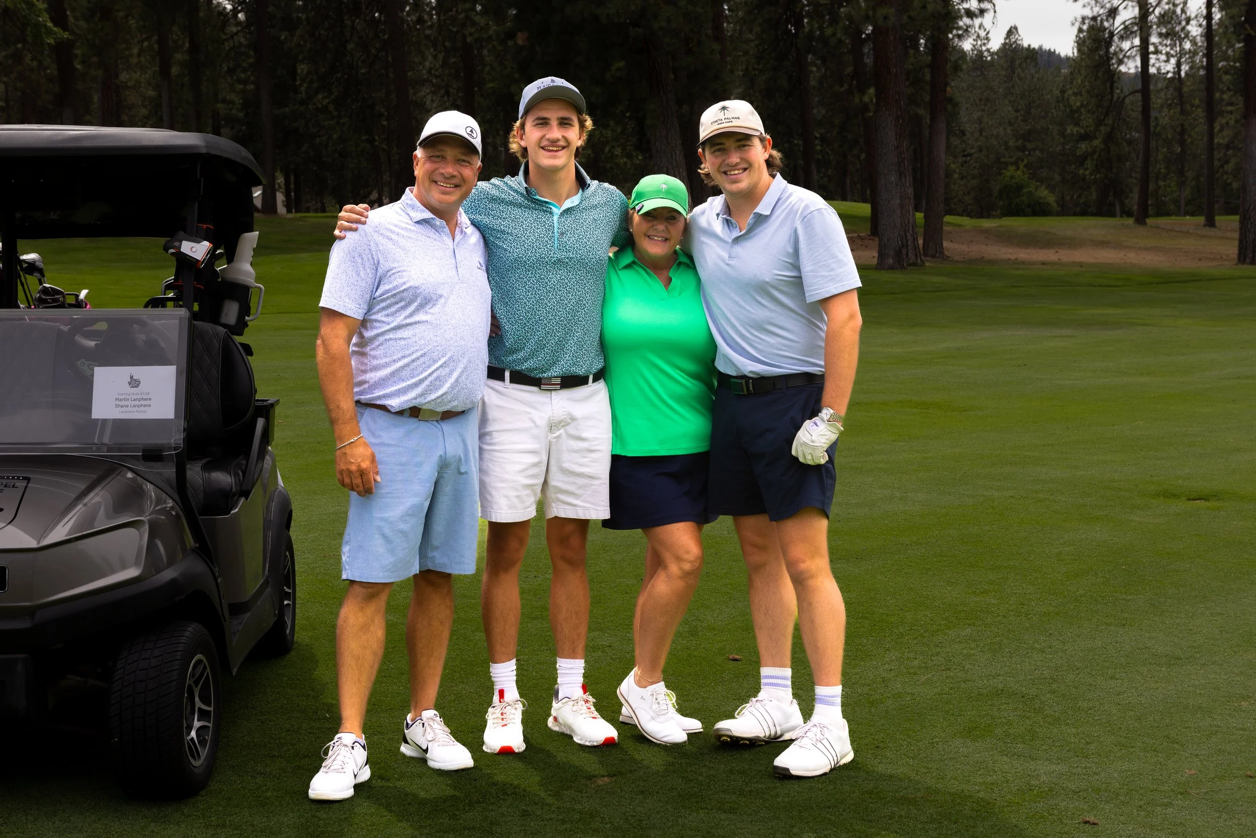 Four people in golf attire standing for a photo on the golf course