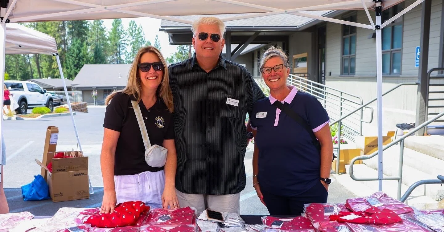 Three people standing at a table of apparel