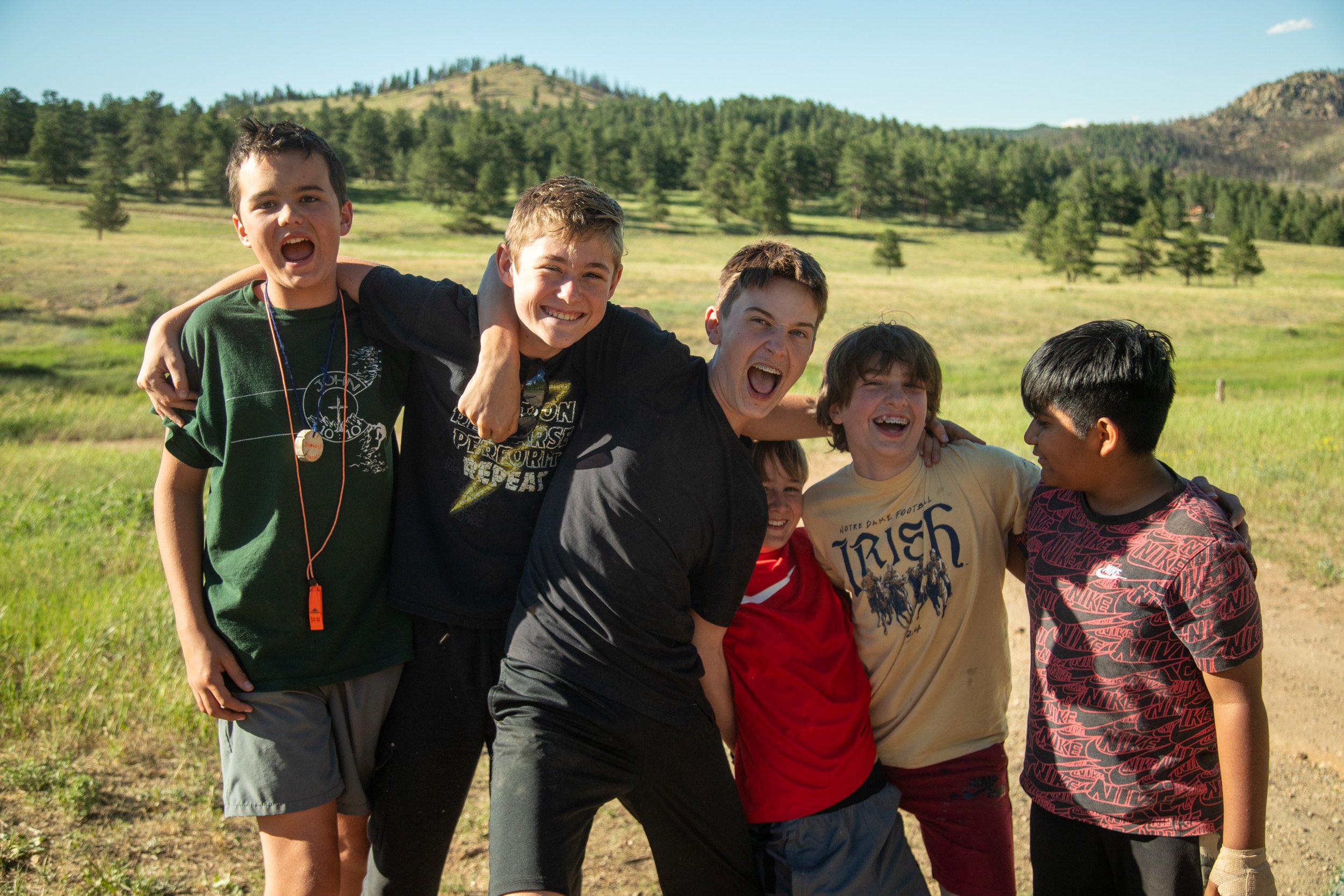 middle school boys standing in front of a mountain meadow