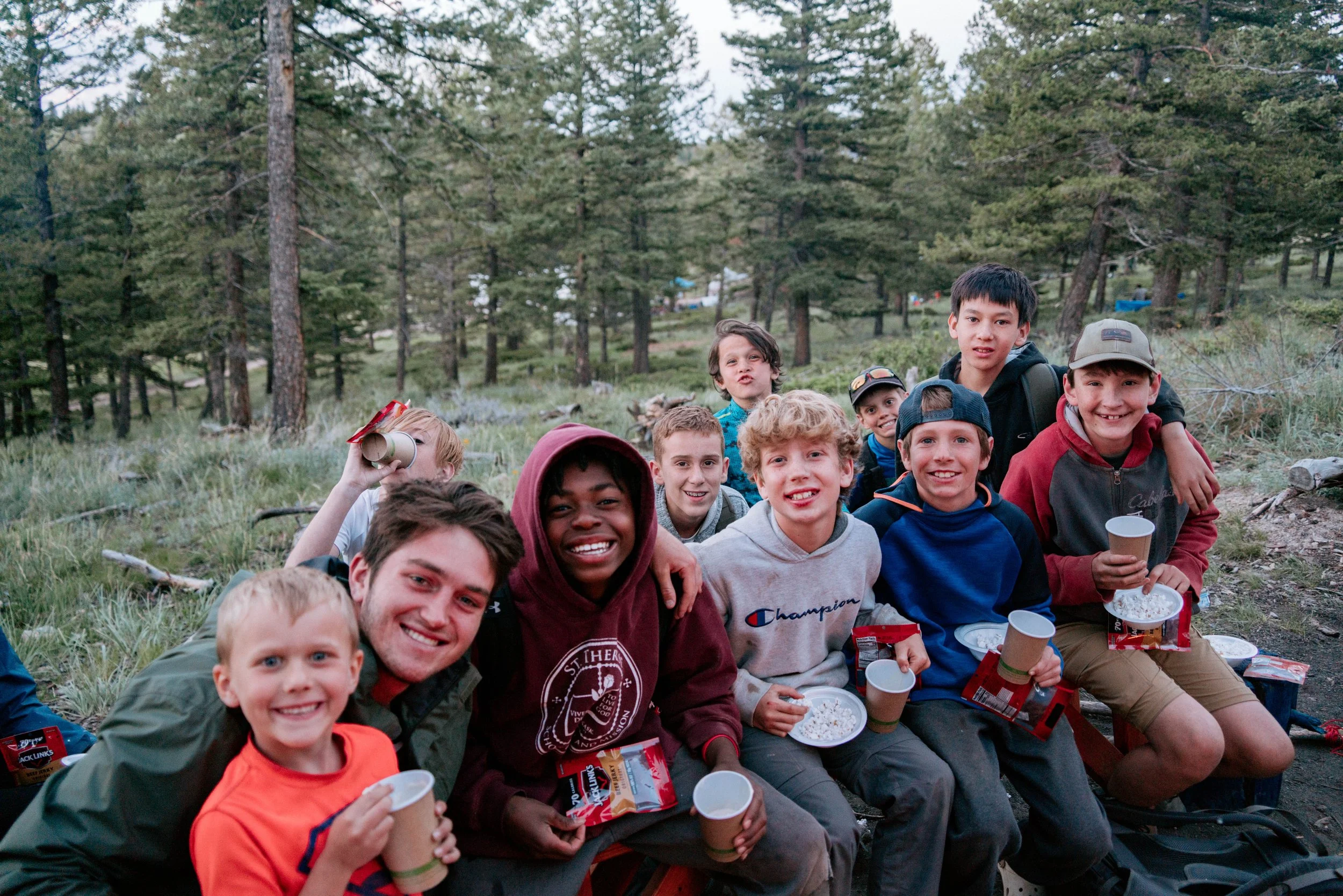 group of middle school boys around a campfire at catholic summer camp in colorado