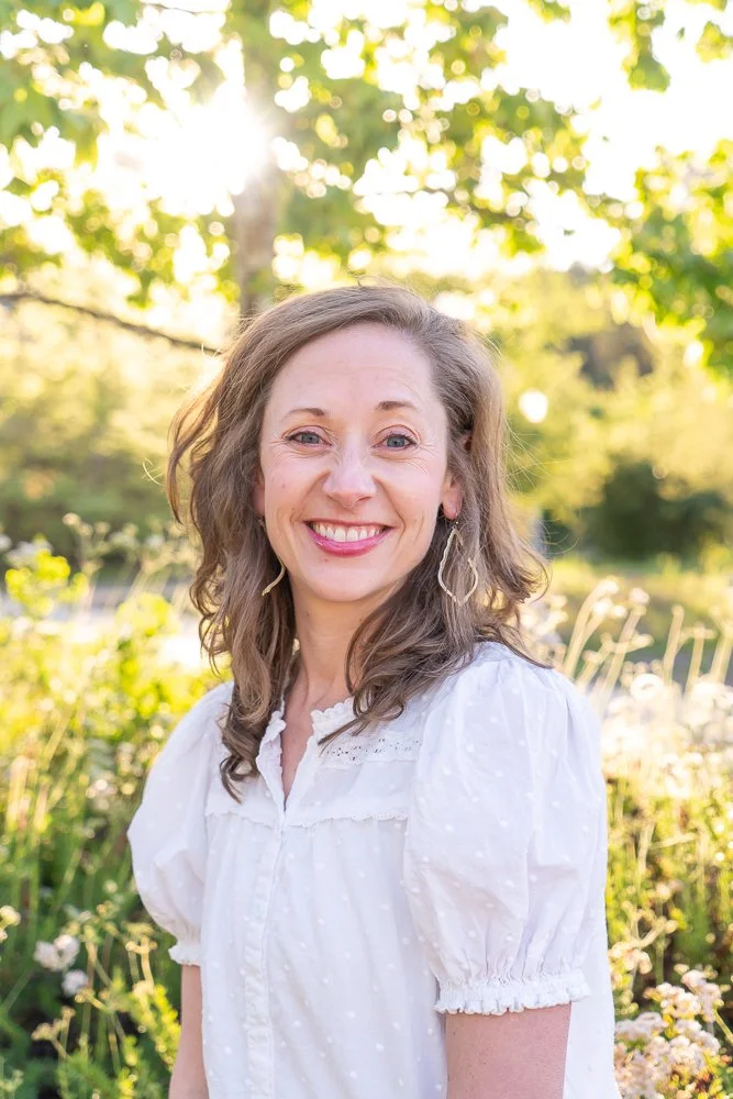 Smiling woman outdoors with trees and sunlight in the background
