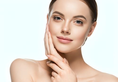 young woman with glowing skin holding hand to face