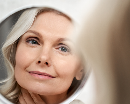 woman looking in mirror smiling at skin