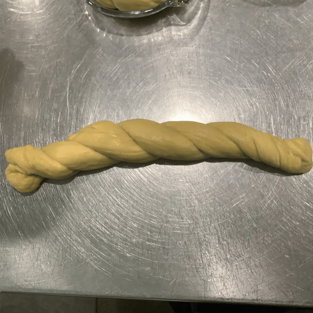 A twisted piece of cookie dough on a metallic surface.