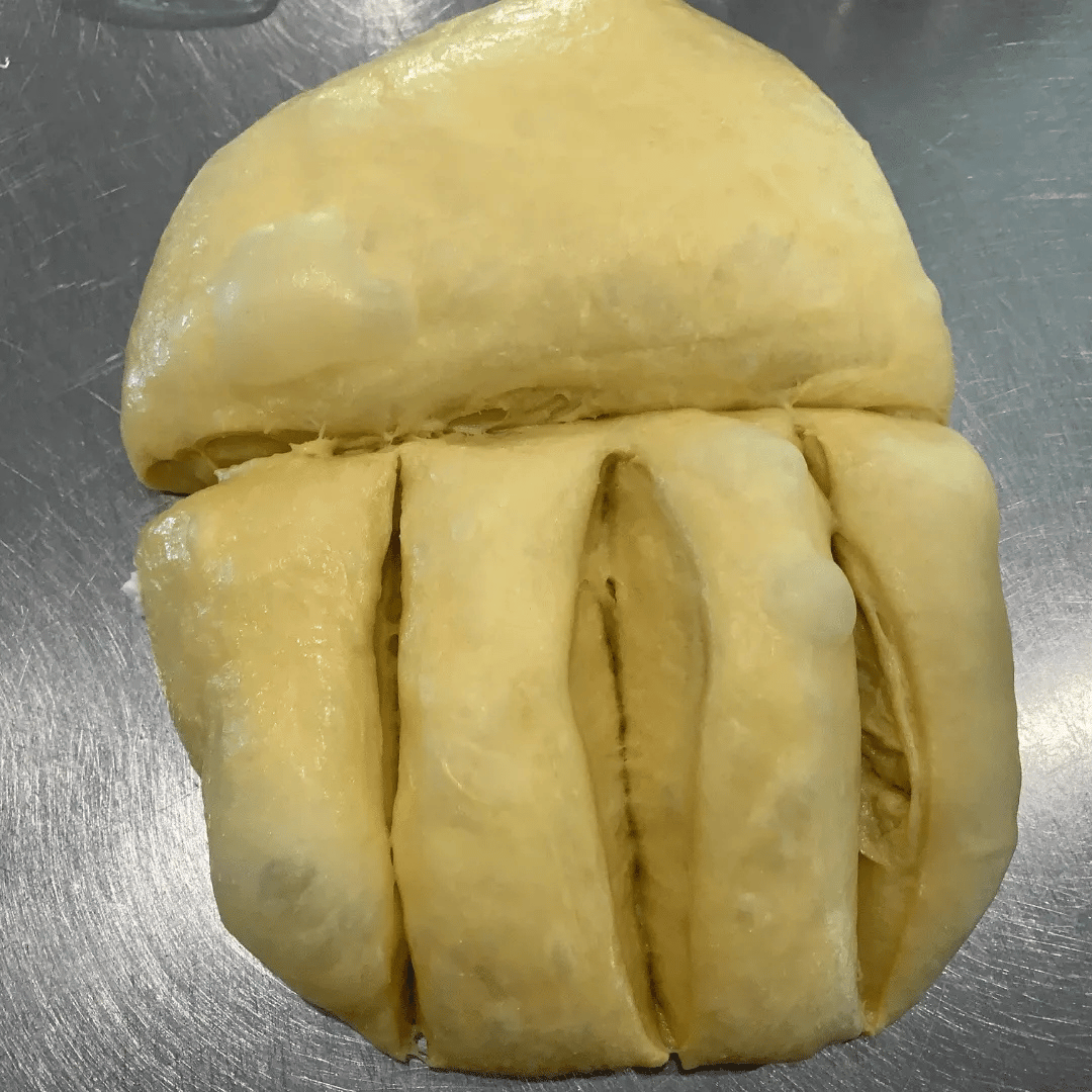 A durian fruit with its outer shell partially removed, showing the yellow flesh inside.