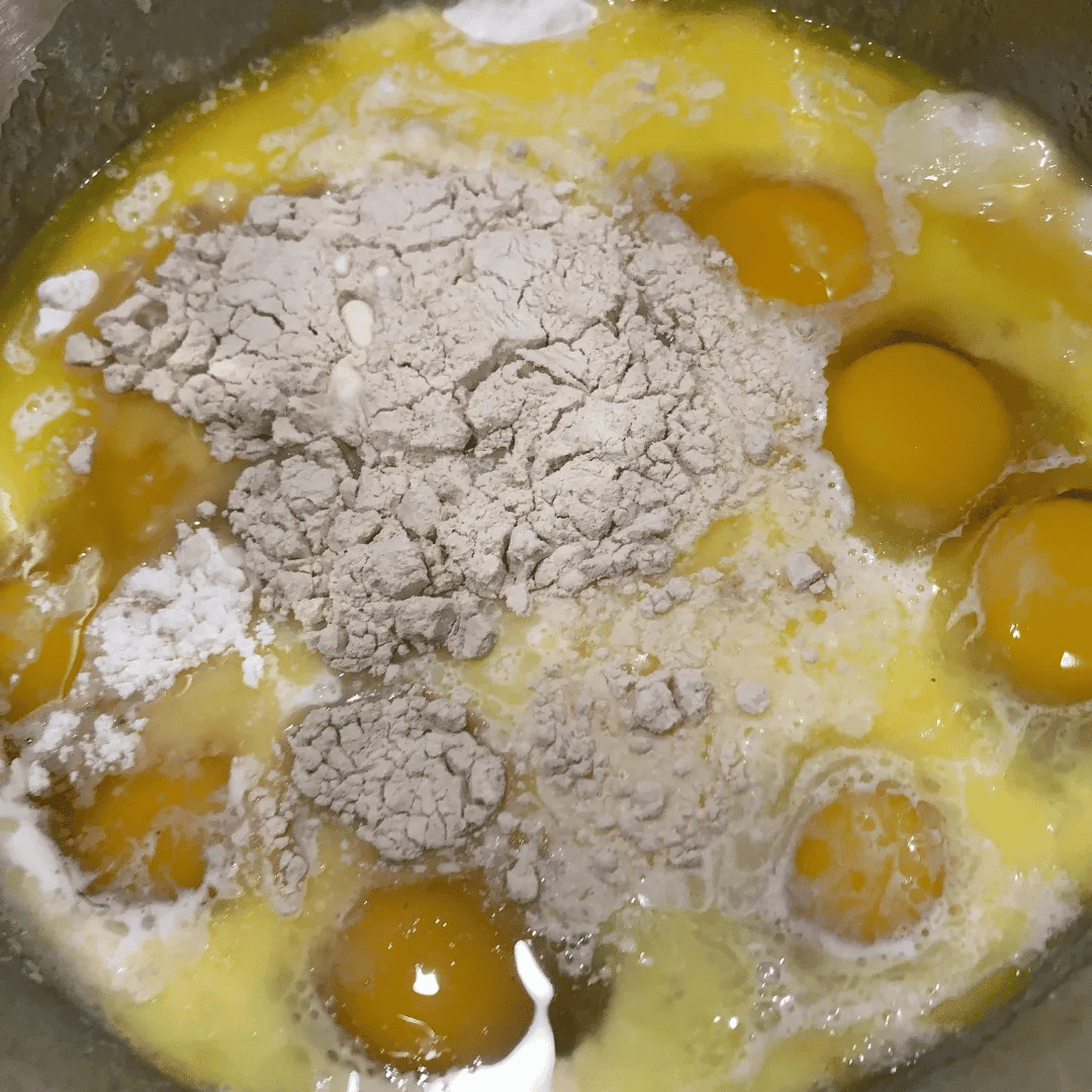 Eggs with flour added in a mixing bowl, ready to be mixed for cooking.