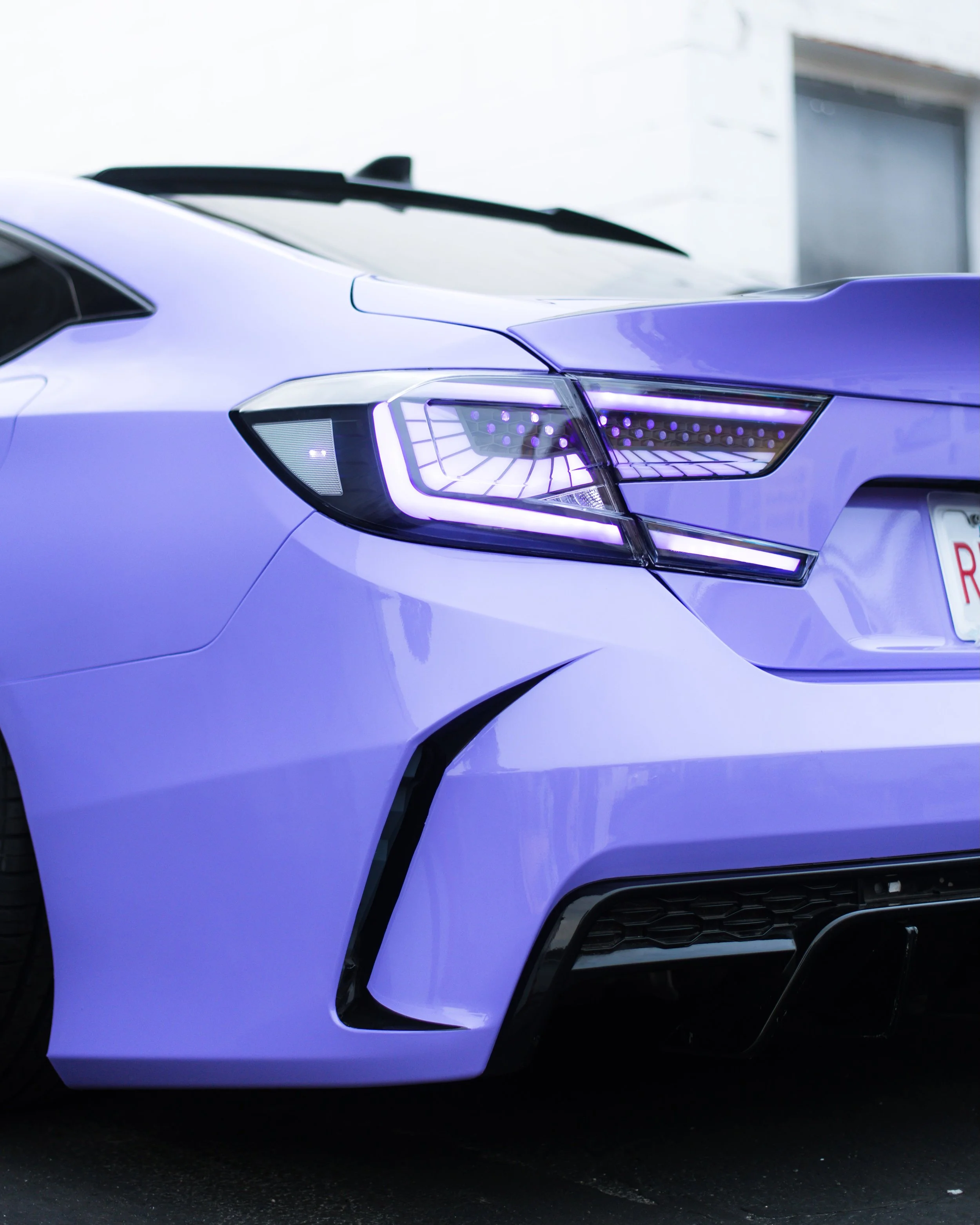 Close-up of front left side of a purple sports car showing headlight, fender, and front bumper.