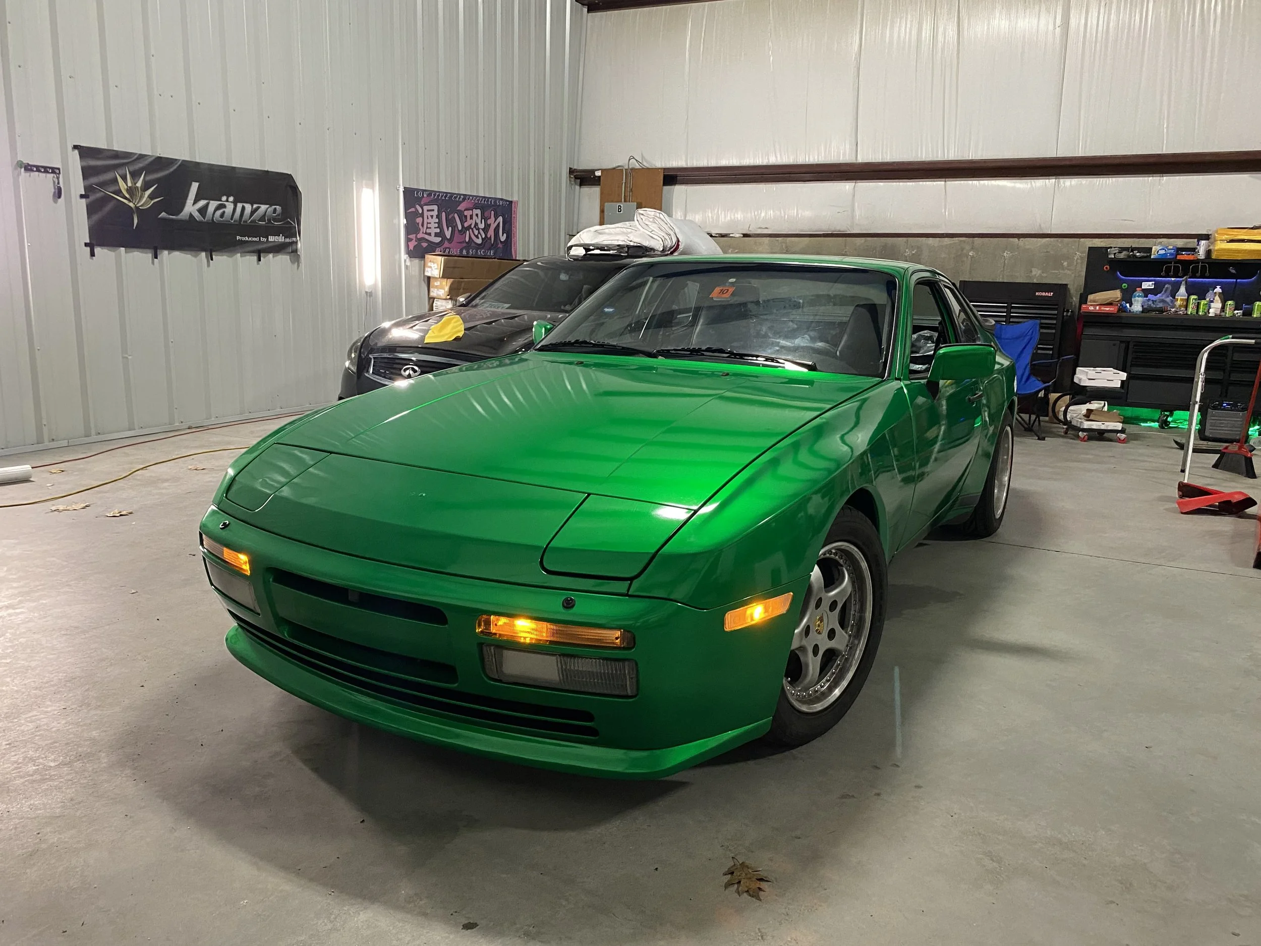 A green sports car parked inside a garage.