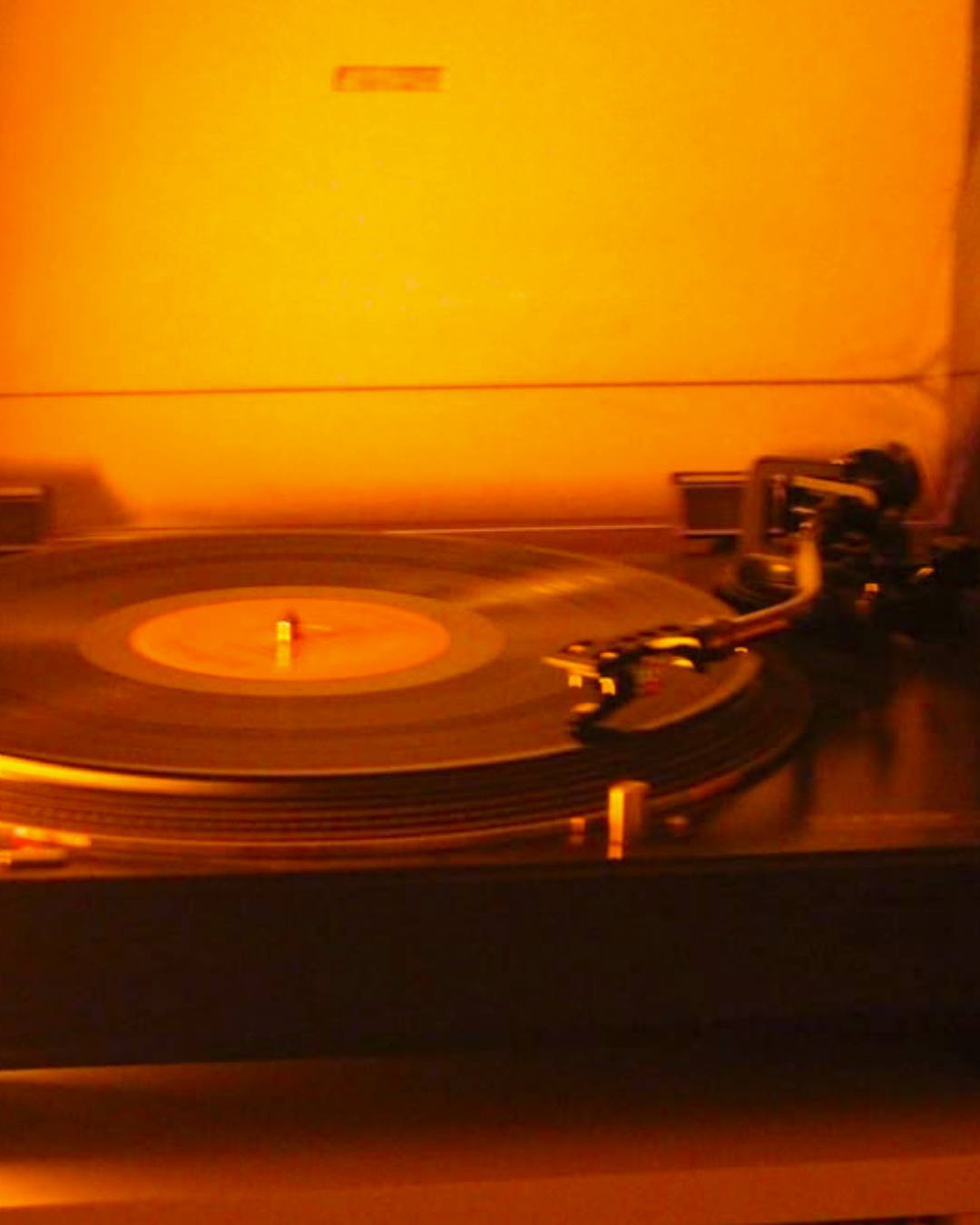 Close-up image of a spinning turntable in a warm orange hue.