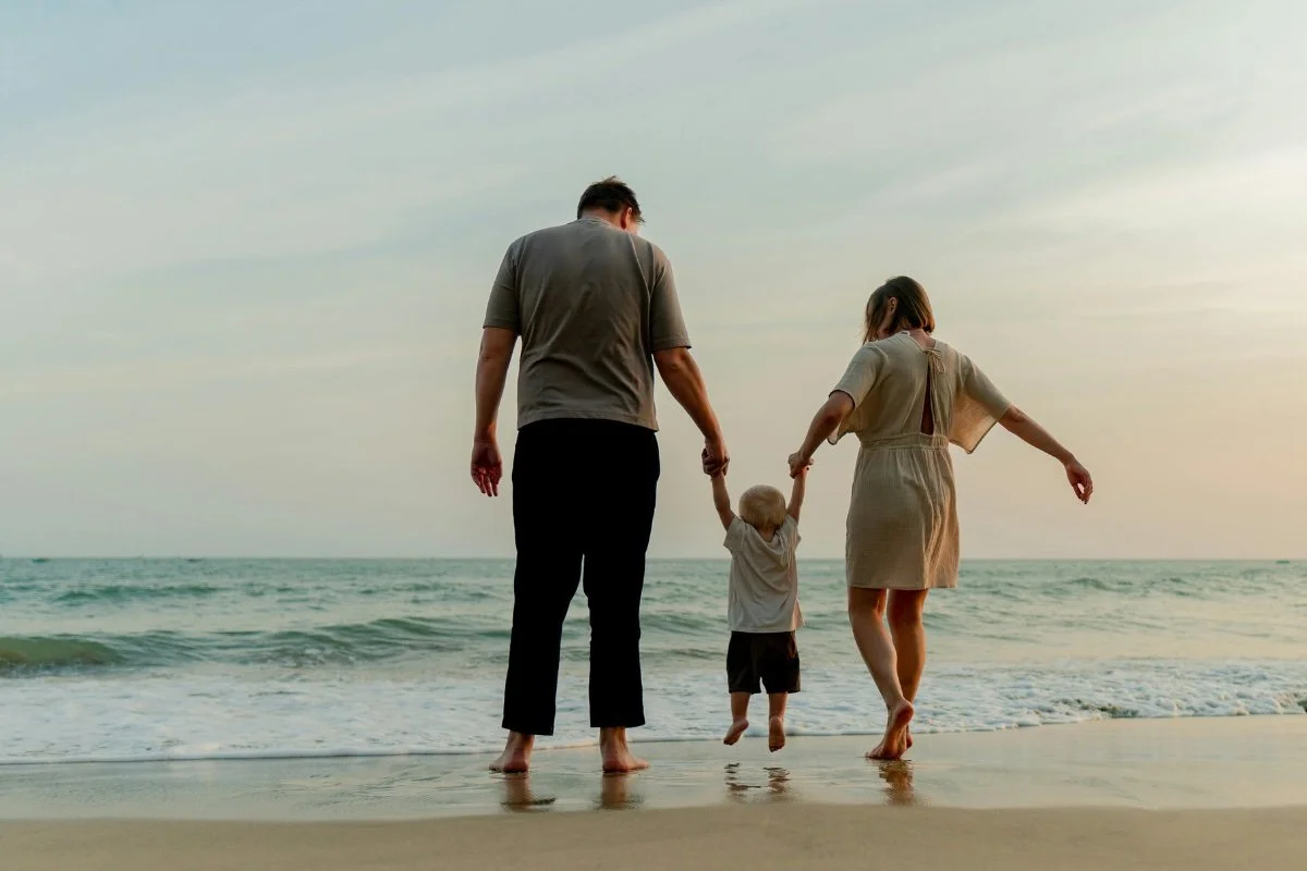 A family walking hand in hand along the beach at sunset, with the ocean waves in the background as an example of adult transitioning off GLP-1