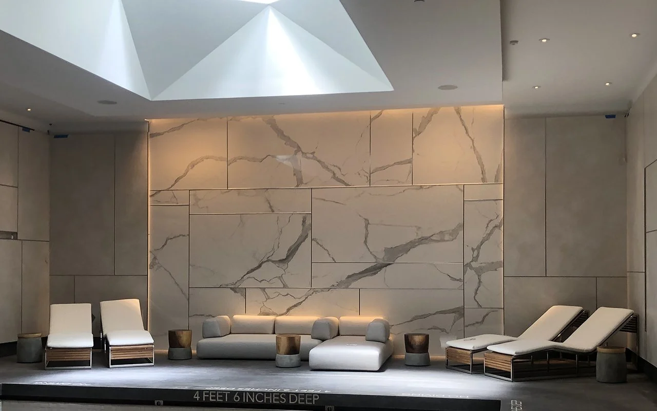 Interior lounge area with modern seating, marble wall, and skylight.