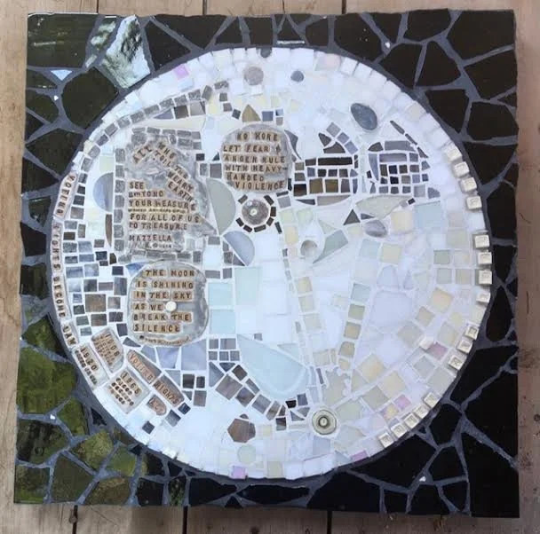 A mosaic clock with a black border, featuring text and small decorative tiles.