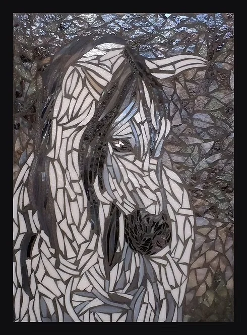 Mosaic art of a white horse with a black mane and background of stones.