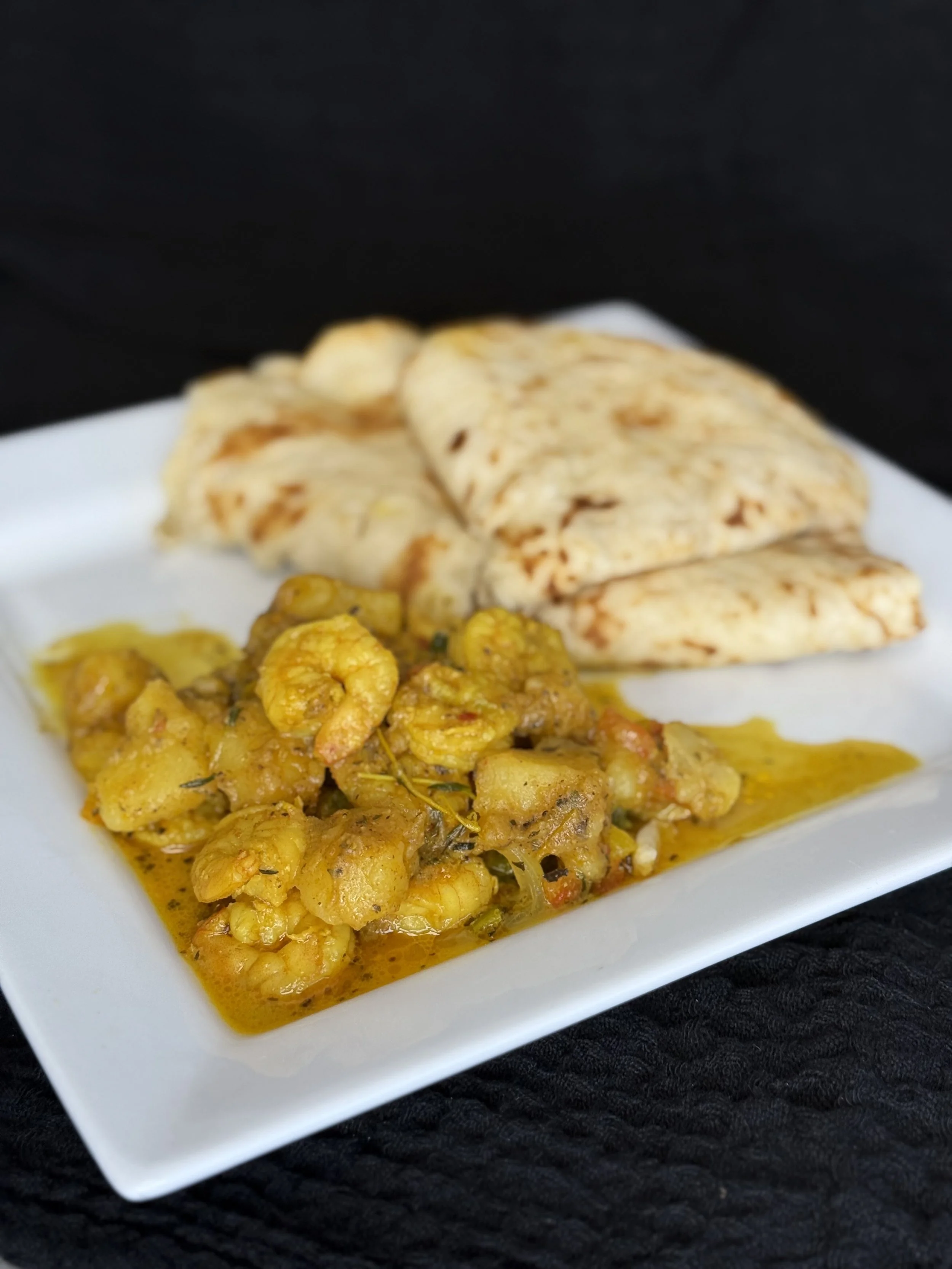 Indian dish with curry cauliflower and chapati on a white plate.