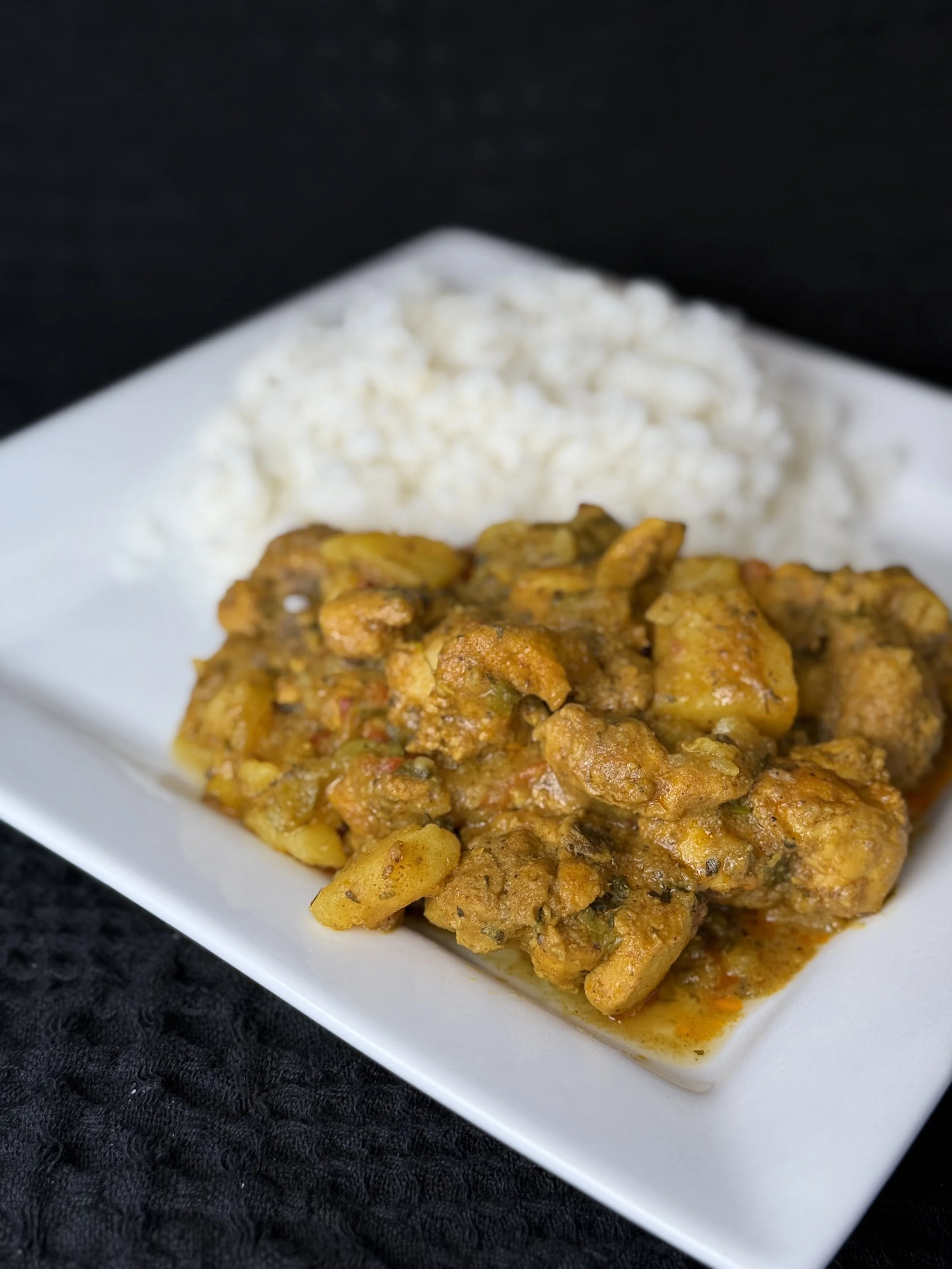 Plate of rice and spicy potato and vegetable stew on a white plate