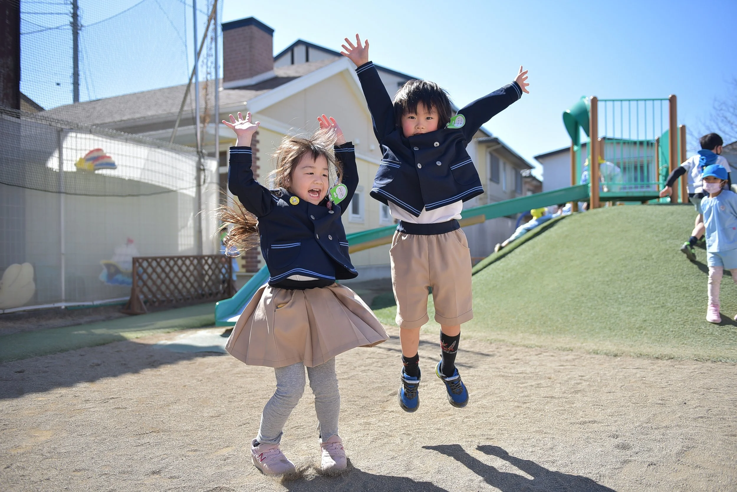幼稚園児の男の子と女の子がジャンプして喜んでいる様子。