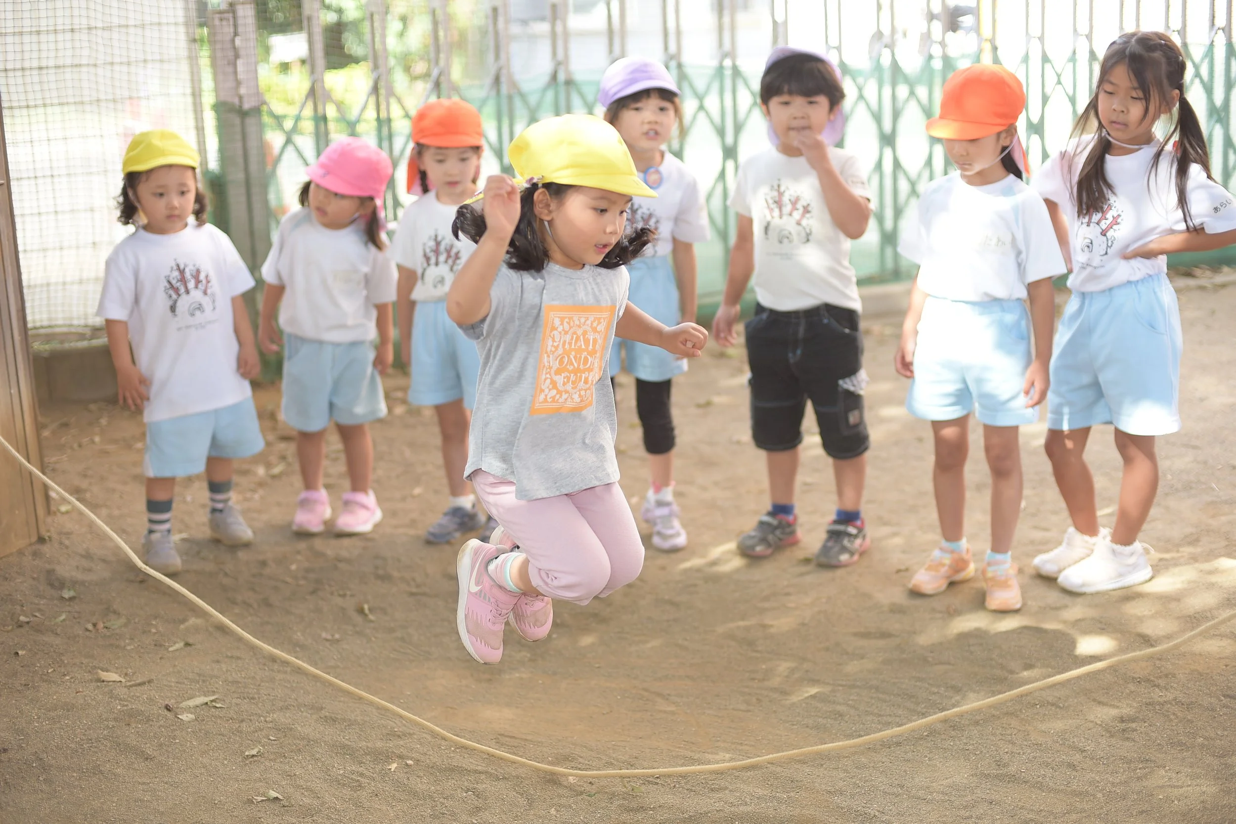 ジャンプする女の子と見守る子供たちがおやつの時間を楽しんでいる