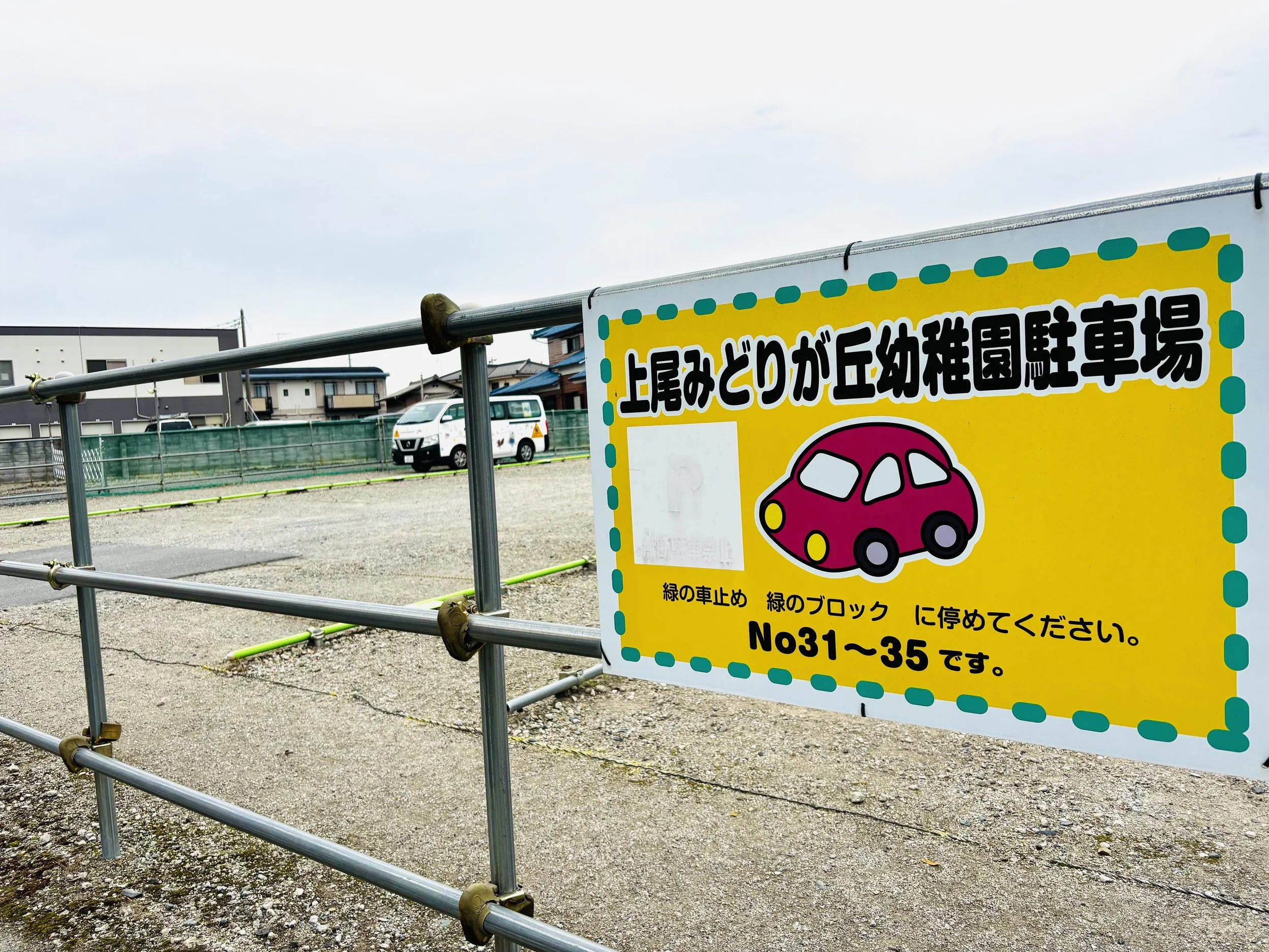 幼稚園の駐車場の案内板。黄色い背景にピンクの車のイラストと日本語の説明。