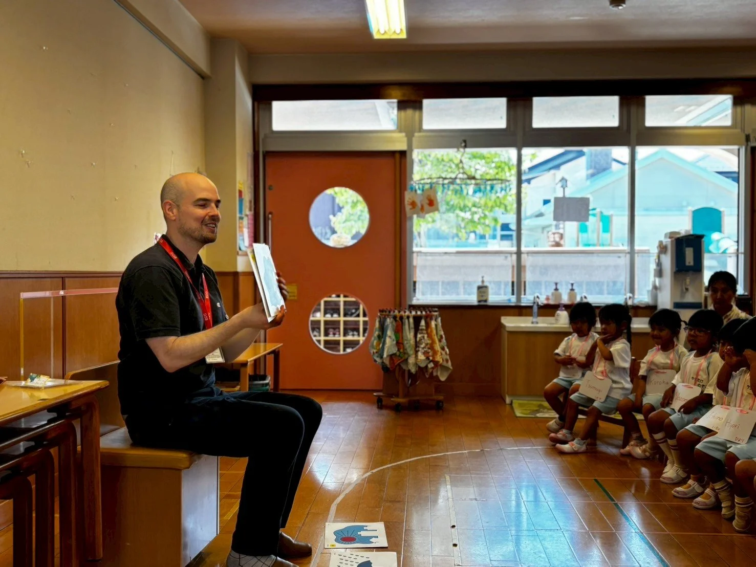 子供たちに絵本を読む男性教師のいる幼稚園の教室の様子