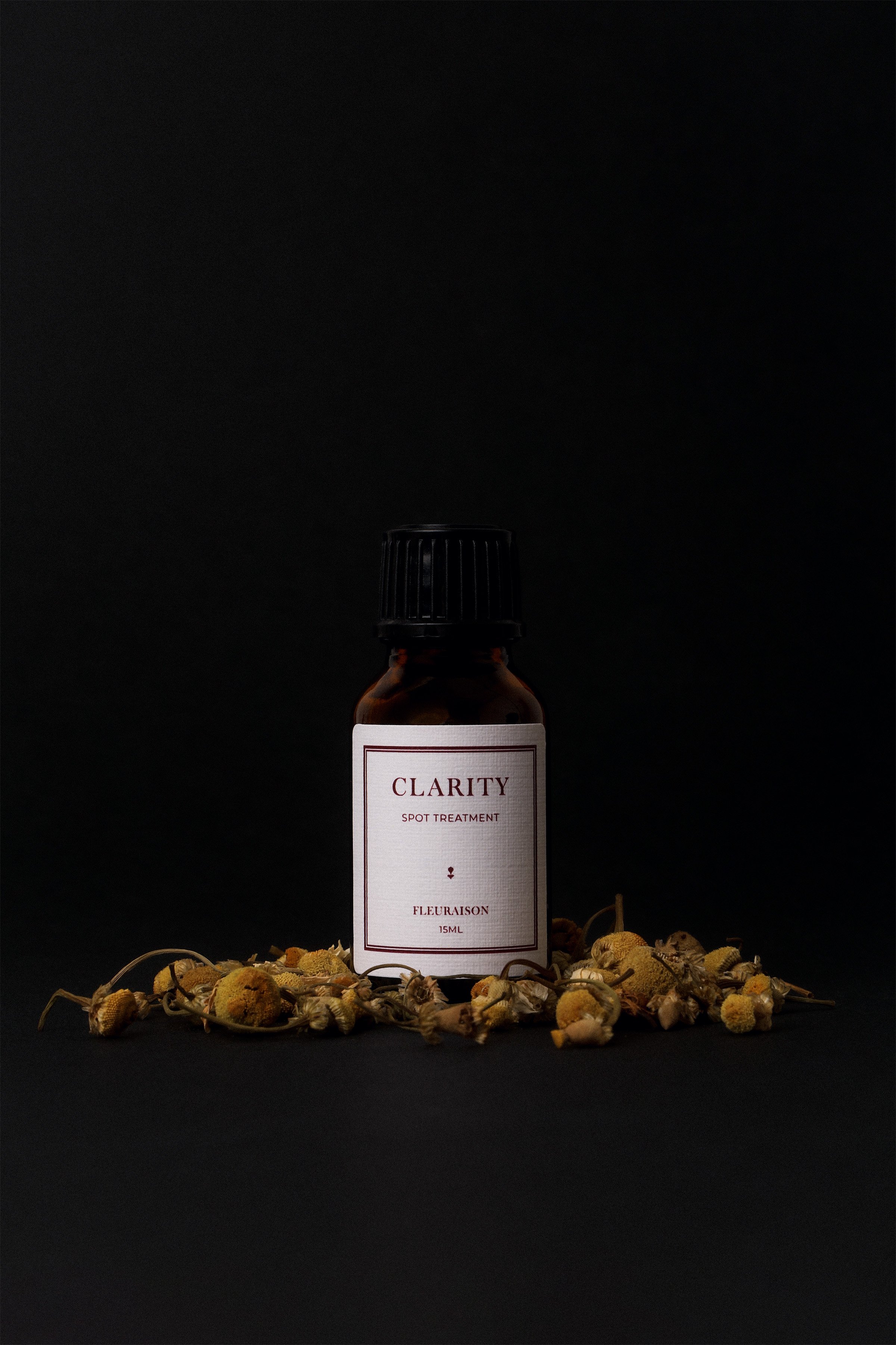 Clarity Botanical Spot Treatment styled with dried chamomile flowers against black backdrop