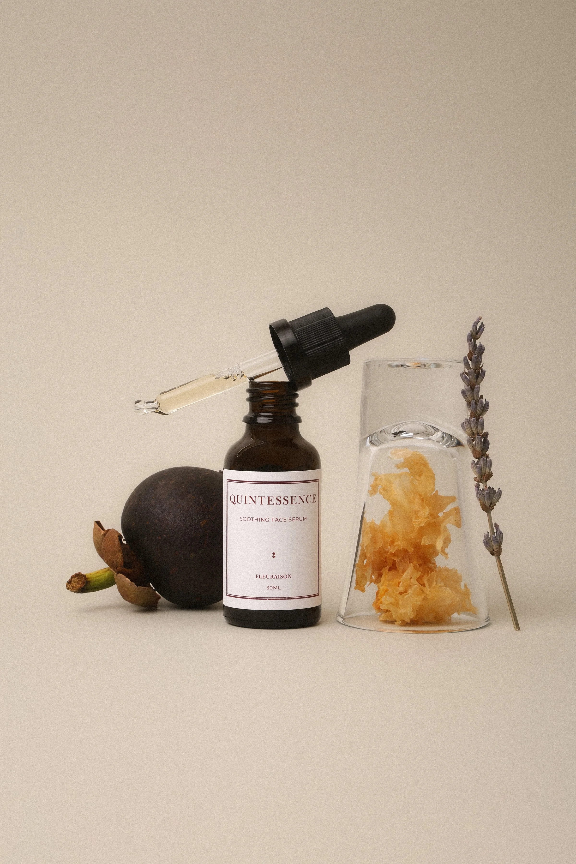Soothing face serum with dropper styled with magnosteen, snow mushroom and lavender against neutral backdrop
