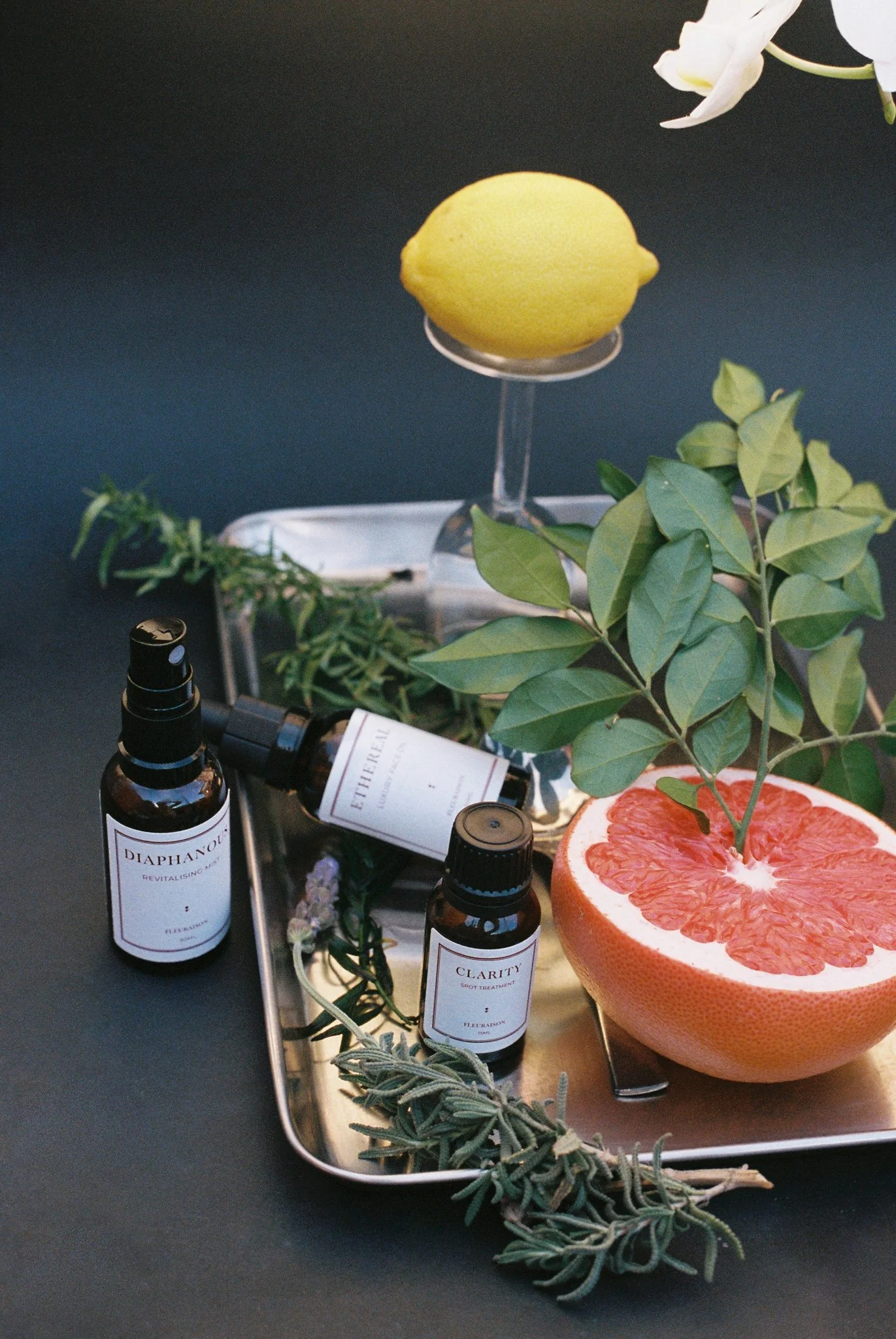 Fleuraison Diaphanous Mist and Clarity Spot Treatment displayed a silver tray, styled with lemon, grapefruit, rosemary and lavender