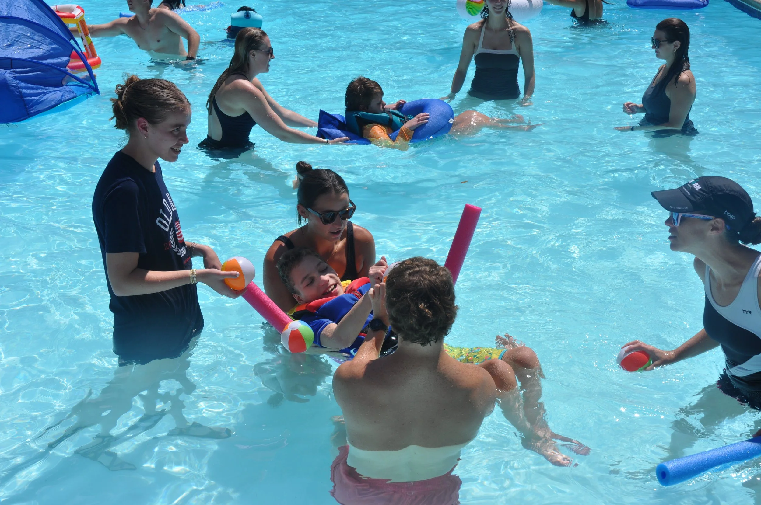 counselors in a pool with child and a flotation device