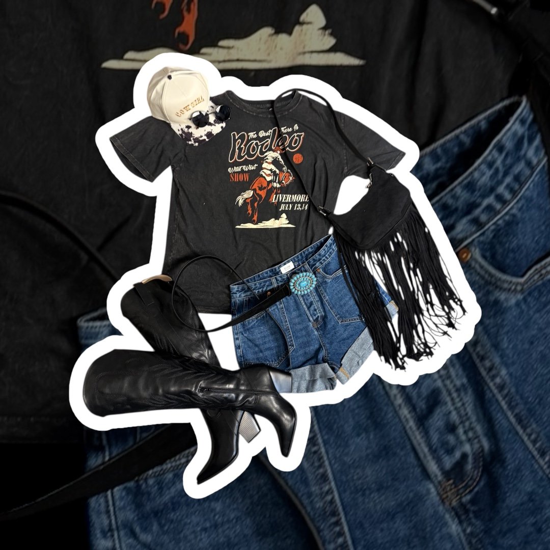 Casual outfit with a black graphic t-shirt featuring a rodeo theme, denim shorts with a large turquoise belt buckle, black knee-high boots, a beige baseball cap, round sunglasses, a small black crossbody bag with fringe, and a black lanyard.