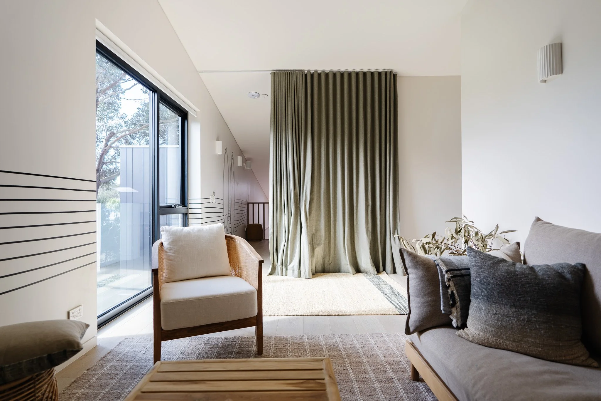 Modern living room with beige and gray furniture, large sliding glass door, green curtains, and minimal decor.